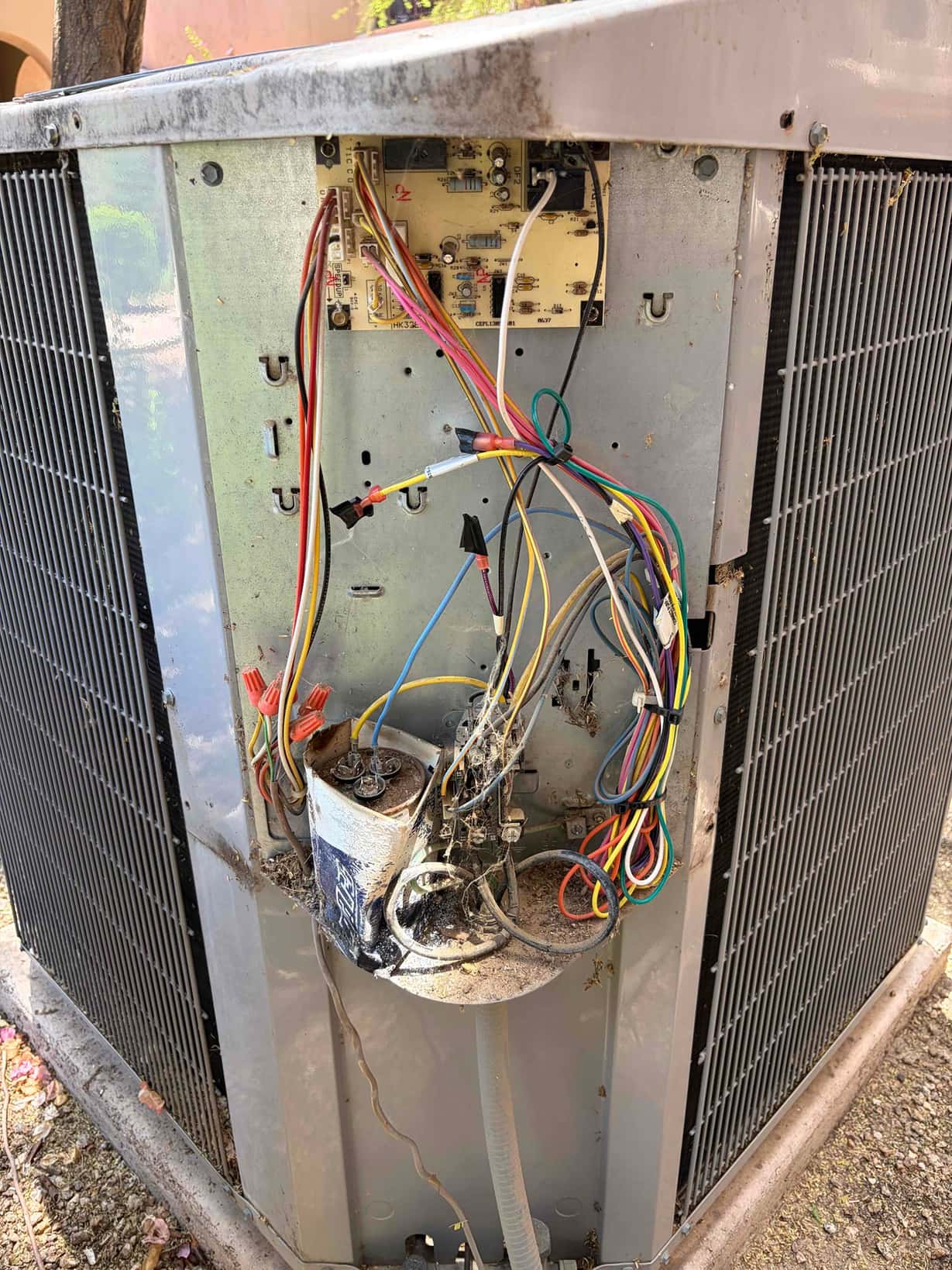 Outdoor condenser control compartment open, with run capacitor heavily corroded and wiring exposed near the control board.