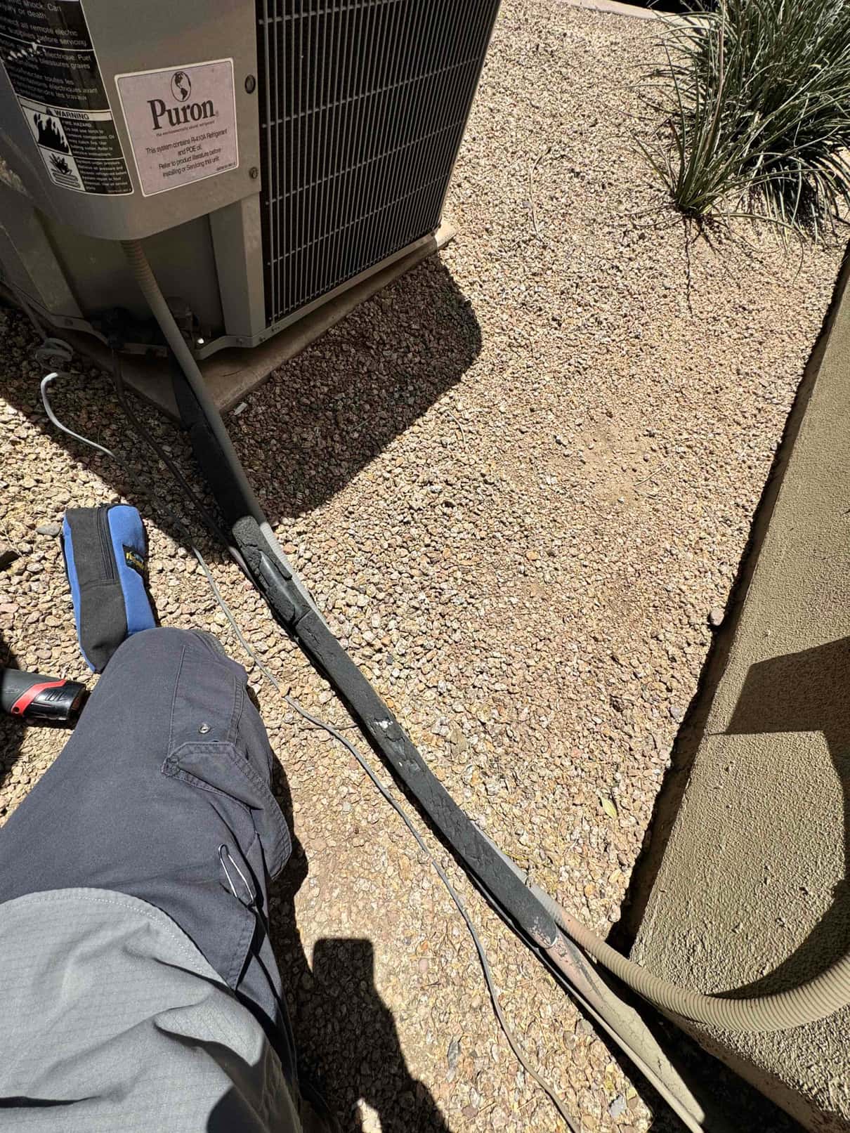 Outdoor condenser with suction line insulation cracked and deteriorated along the run beside the unit.