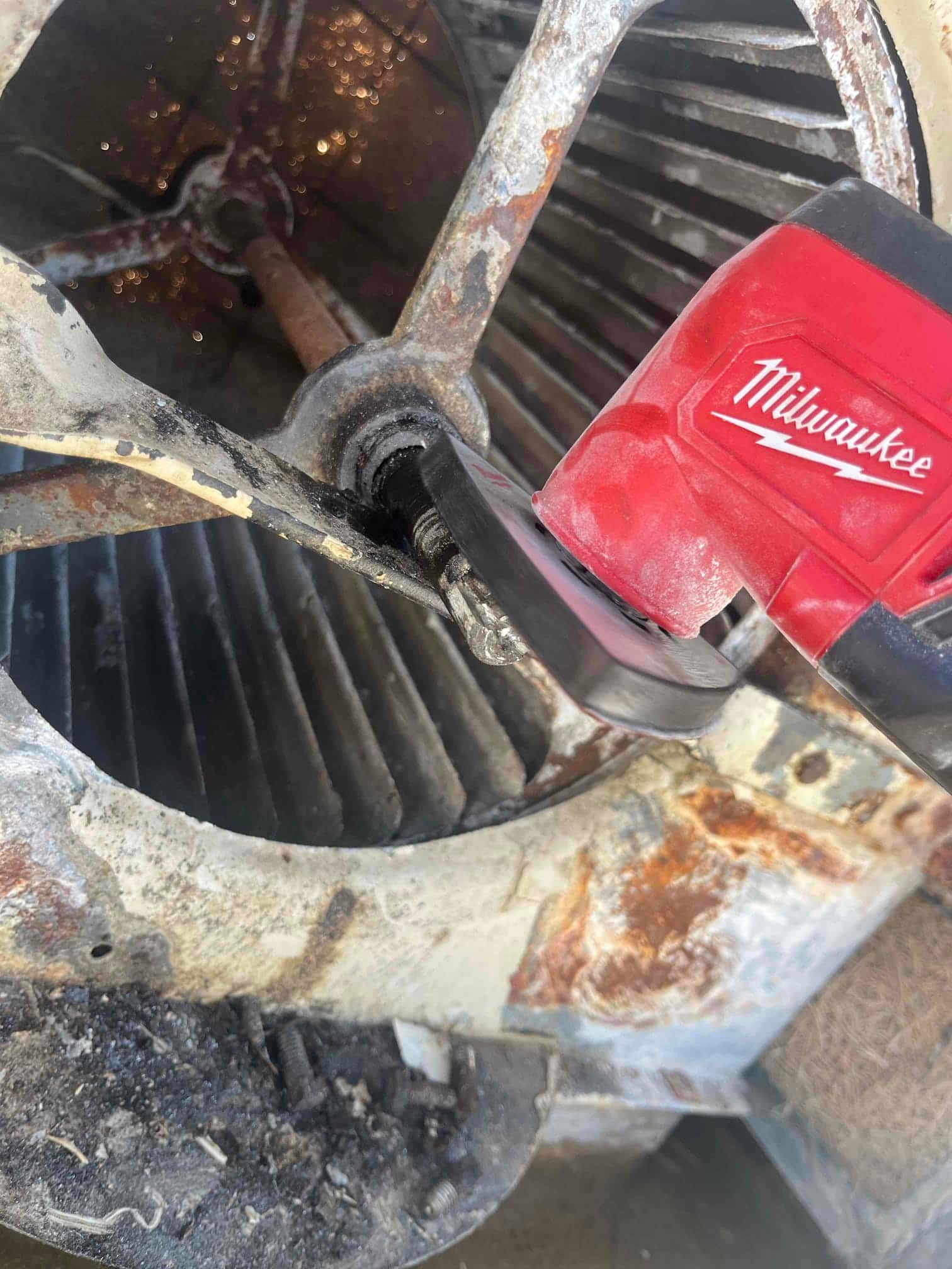 Reciprocating saw blade is positioned at the blower wheel hub on a heavily rusted assembly.