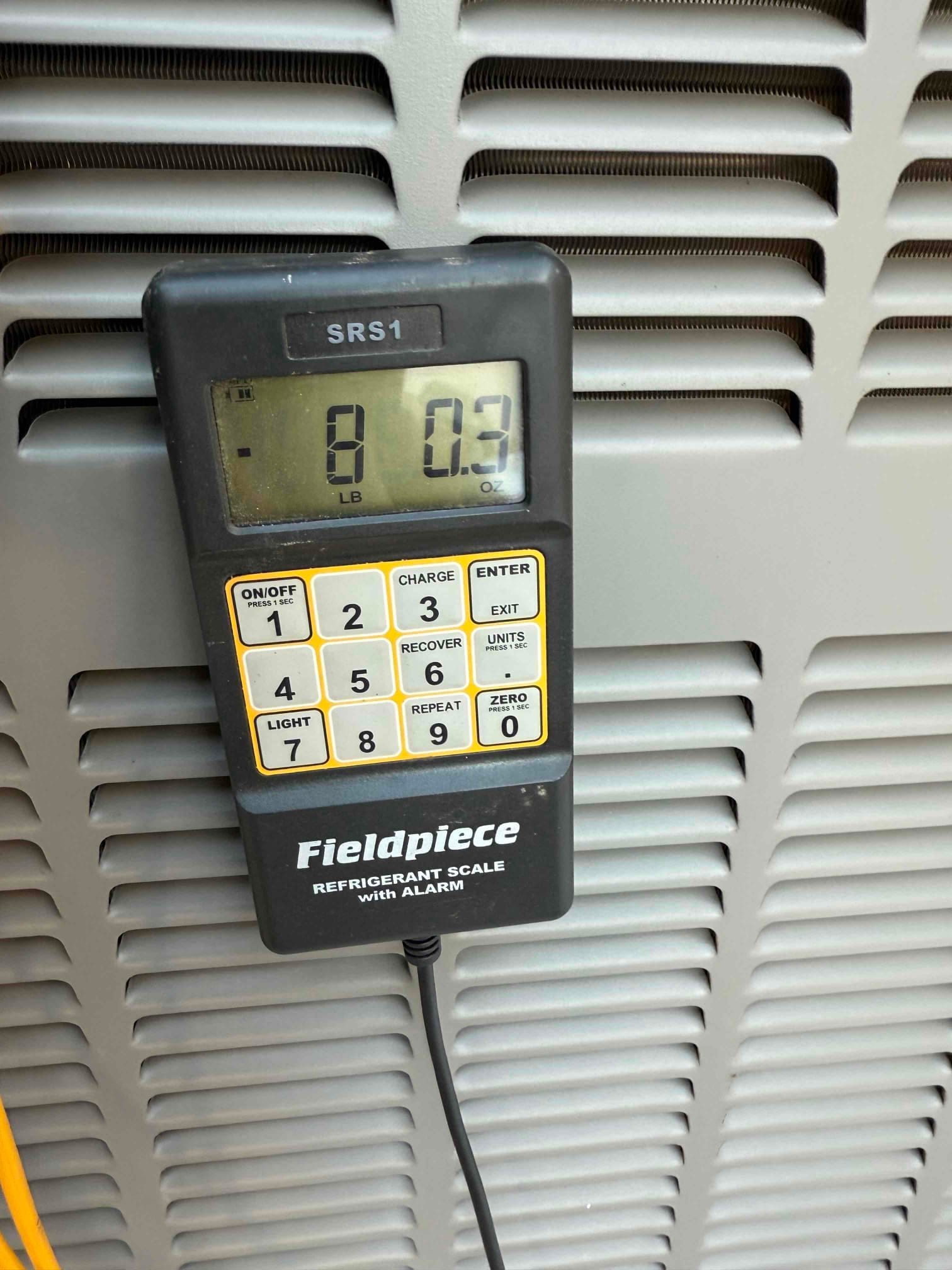 Refrigerant scale photographed during the service visit; no numerical reading is transcribed.