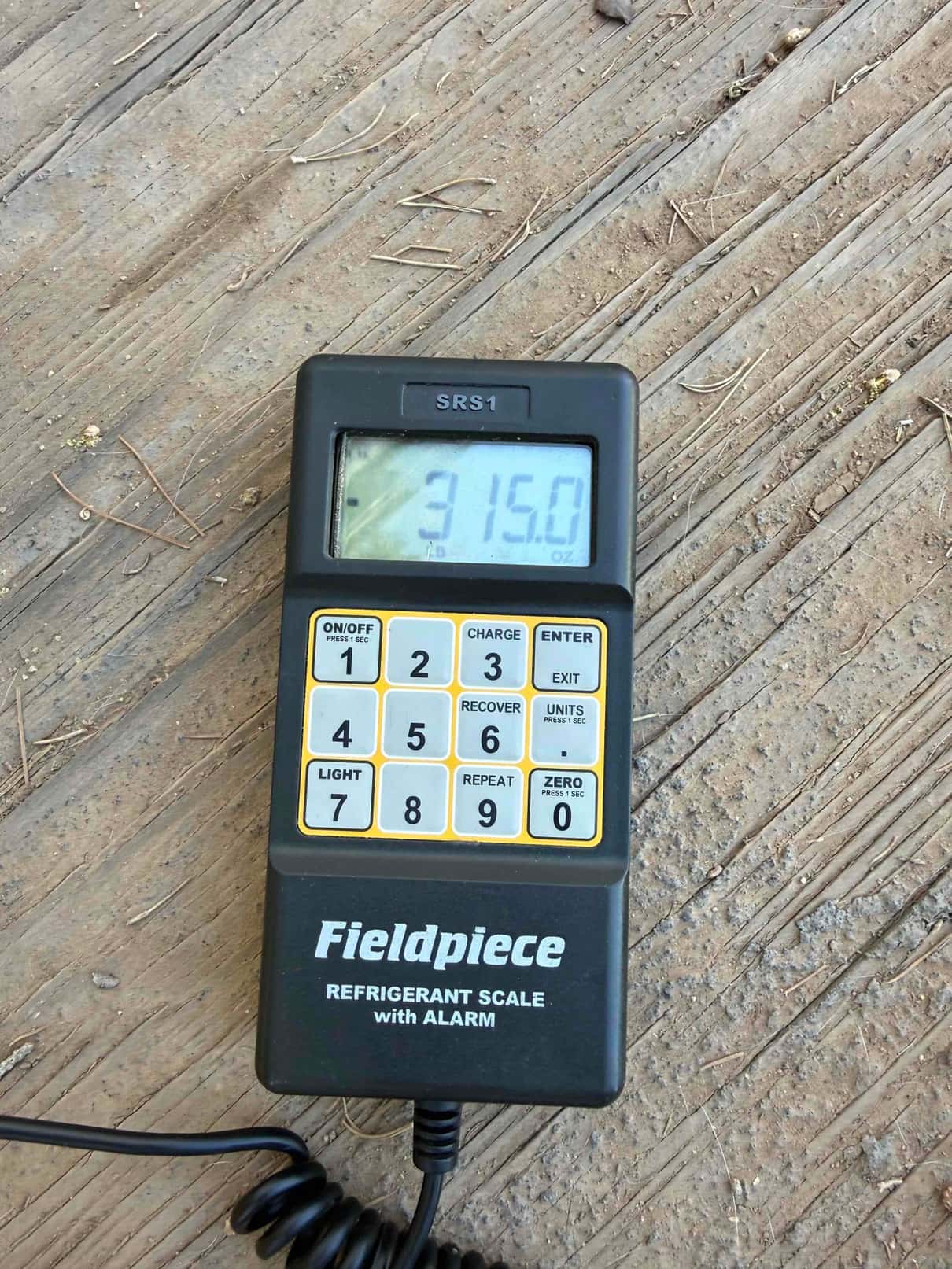Refrigerant scale photographed during the service visit; no numerical reading is transcribed.