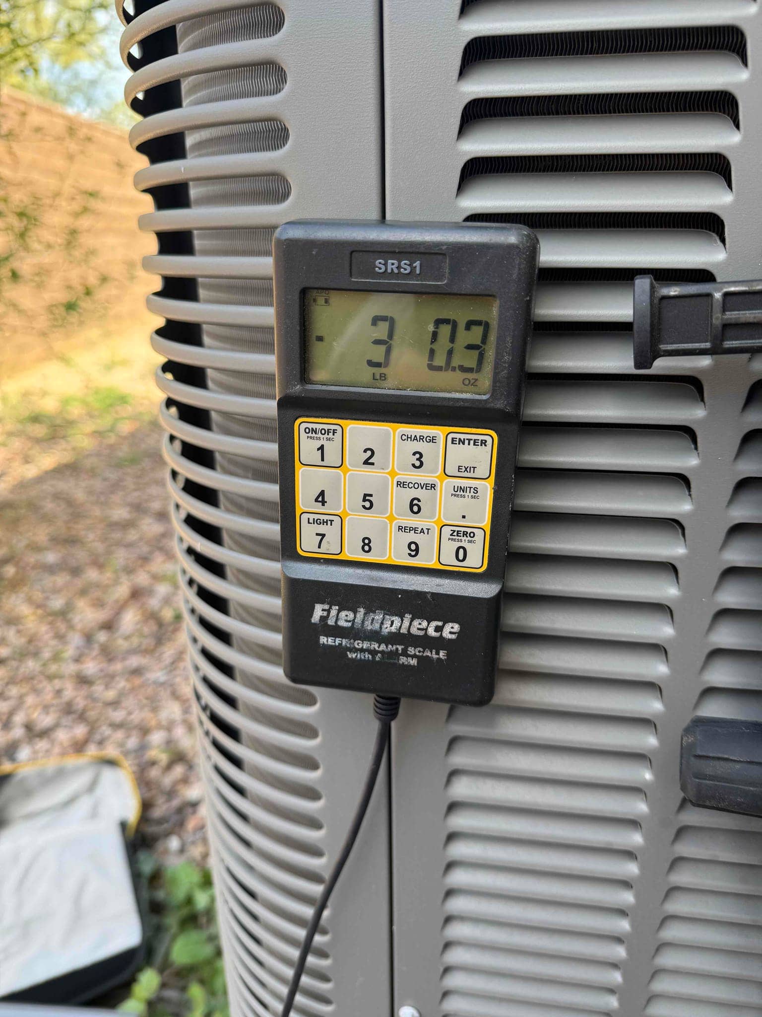 Refrigerant scale photographed during the service visit; no numerical reading is transcribed.