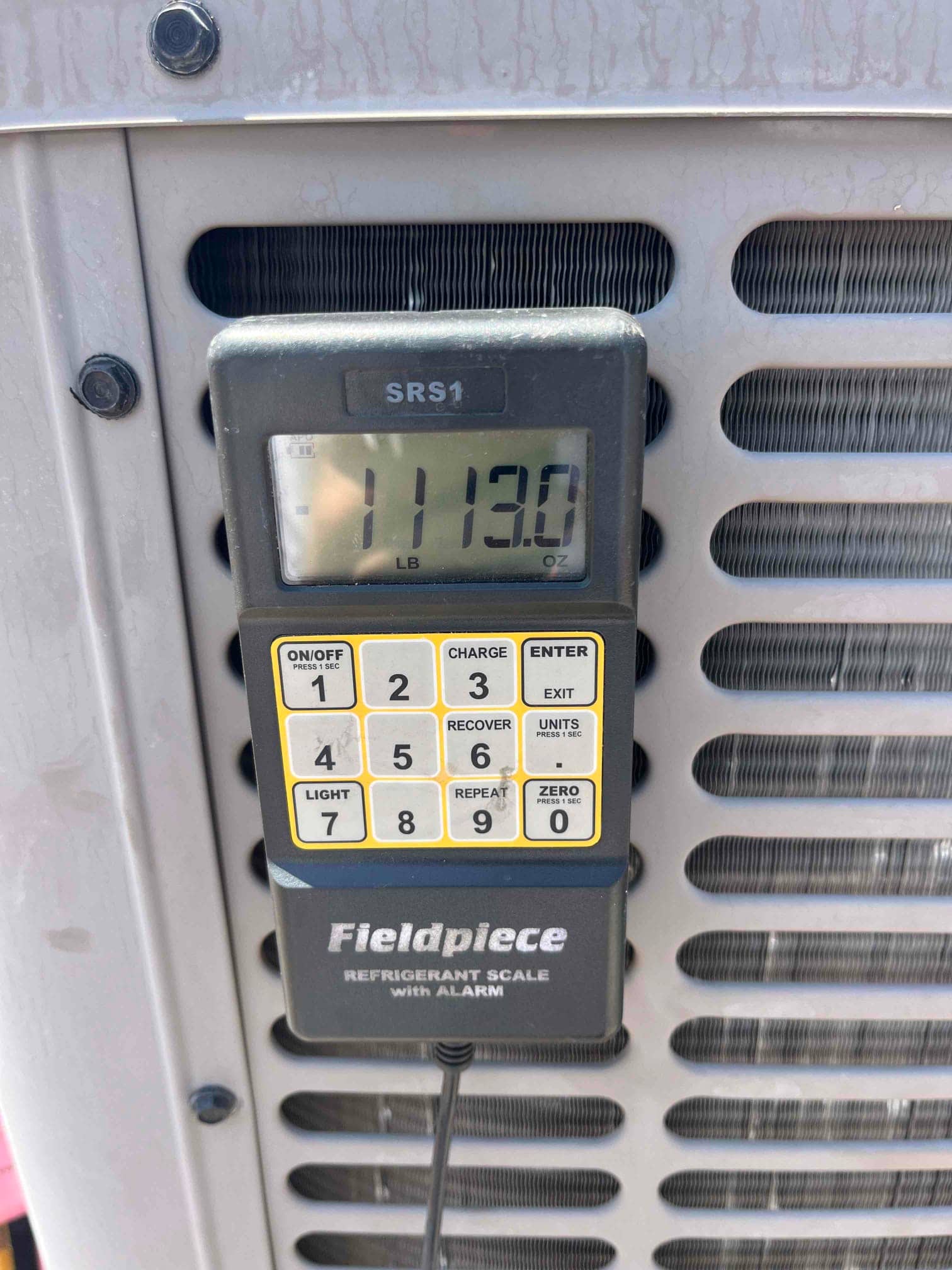 Refrigerant scale photographed during the service visit; no numerical reading is transcribed.