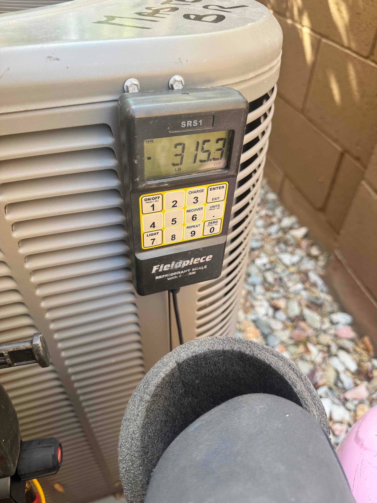 Refrigerant scale photographed during the service visit; no numerical reading is transcribed.