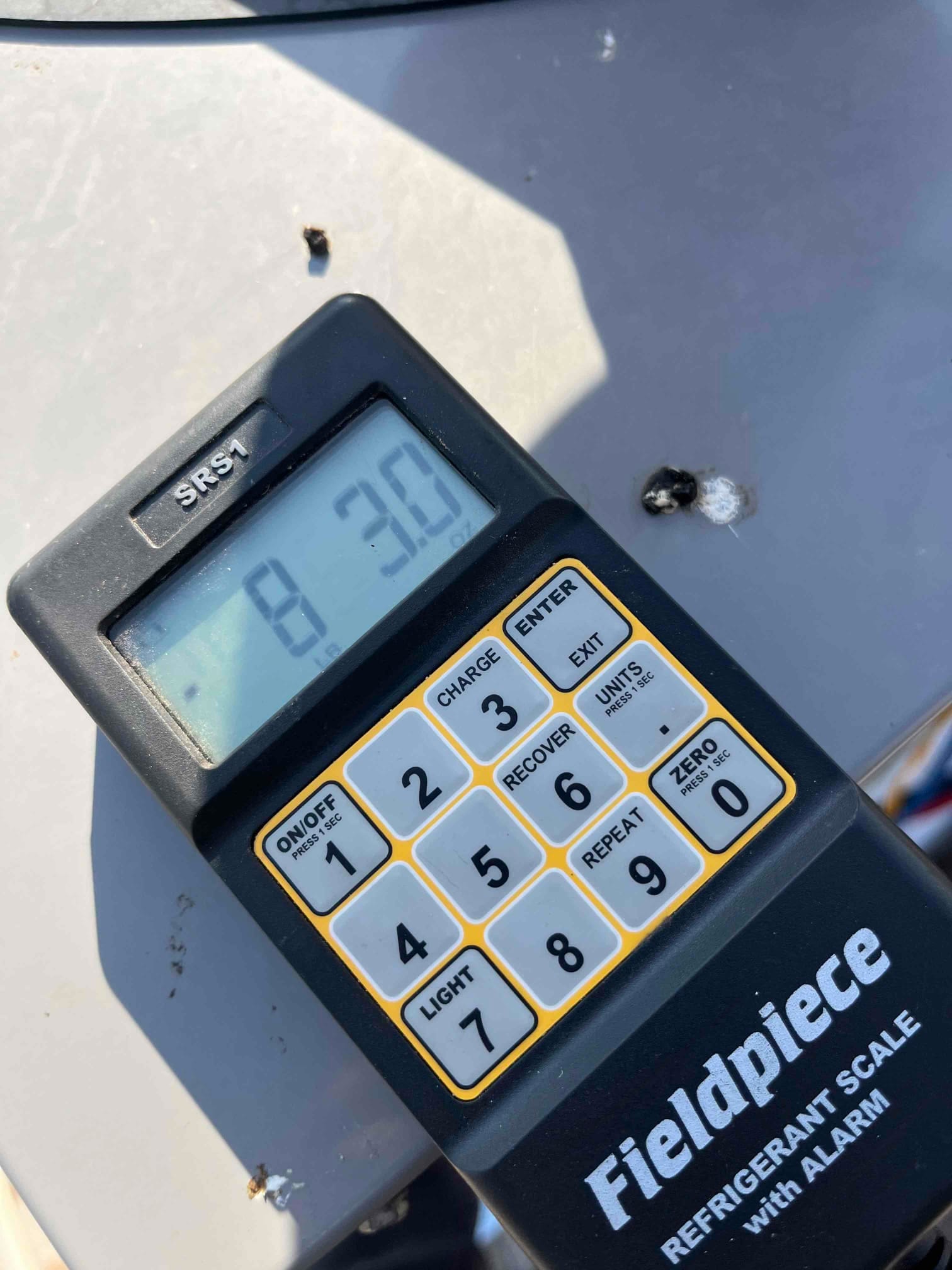 Refrigerant scale photographed during the service visit; no numerical reading is transcribed.