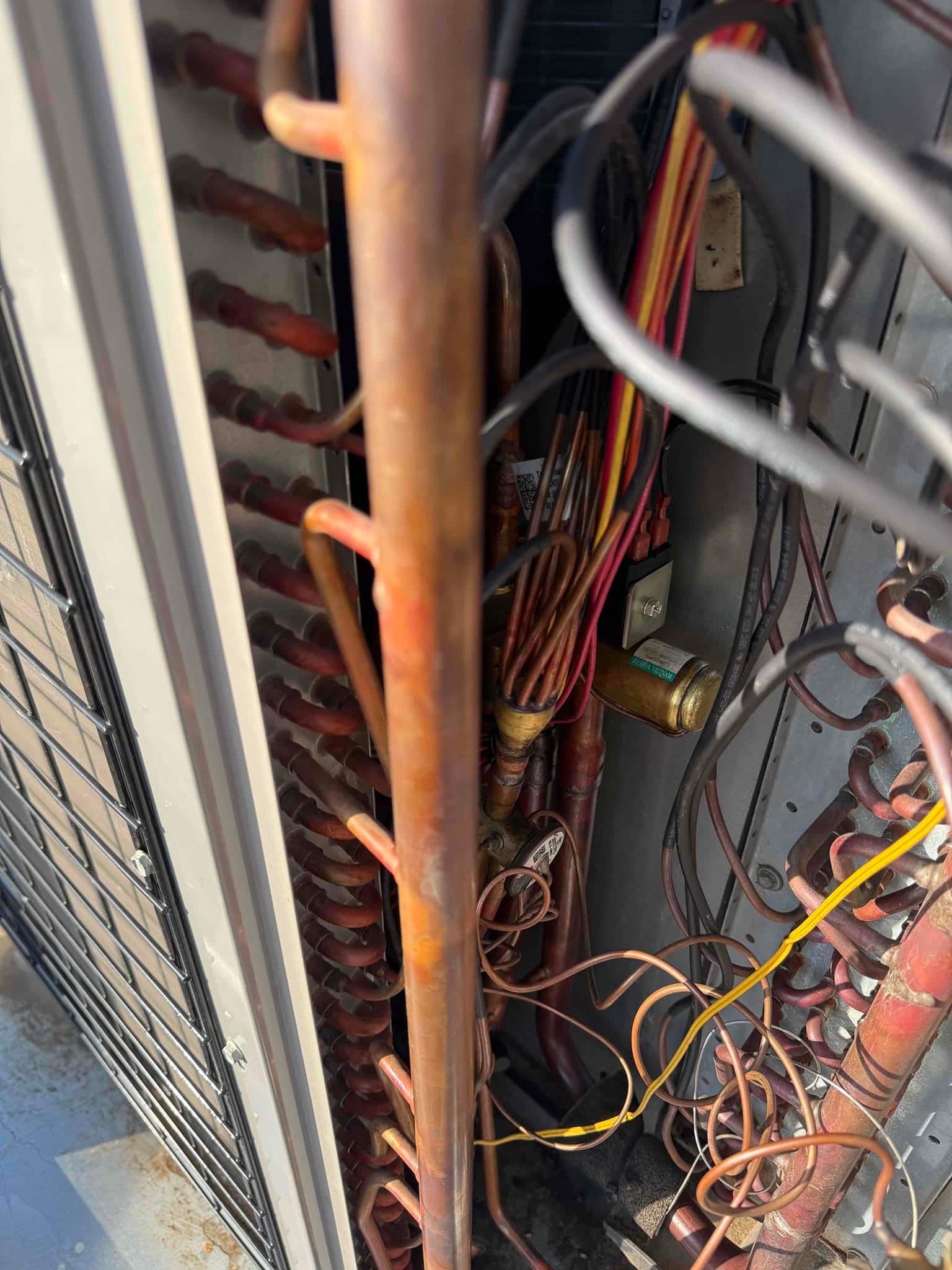 Refrigerant tubing, coil connections, and wiring visible inside the open outdoor condenser cabinet during inspection.