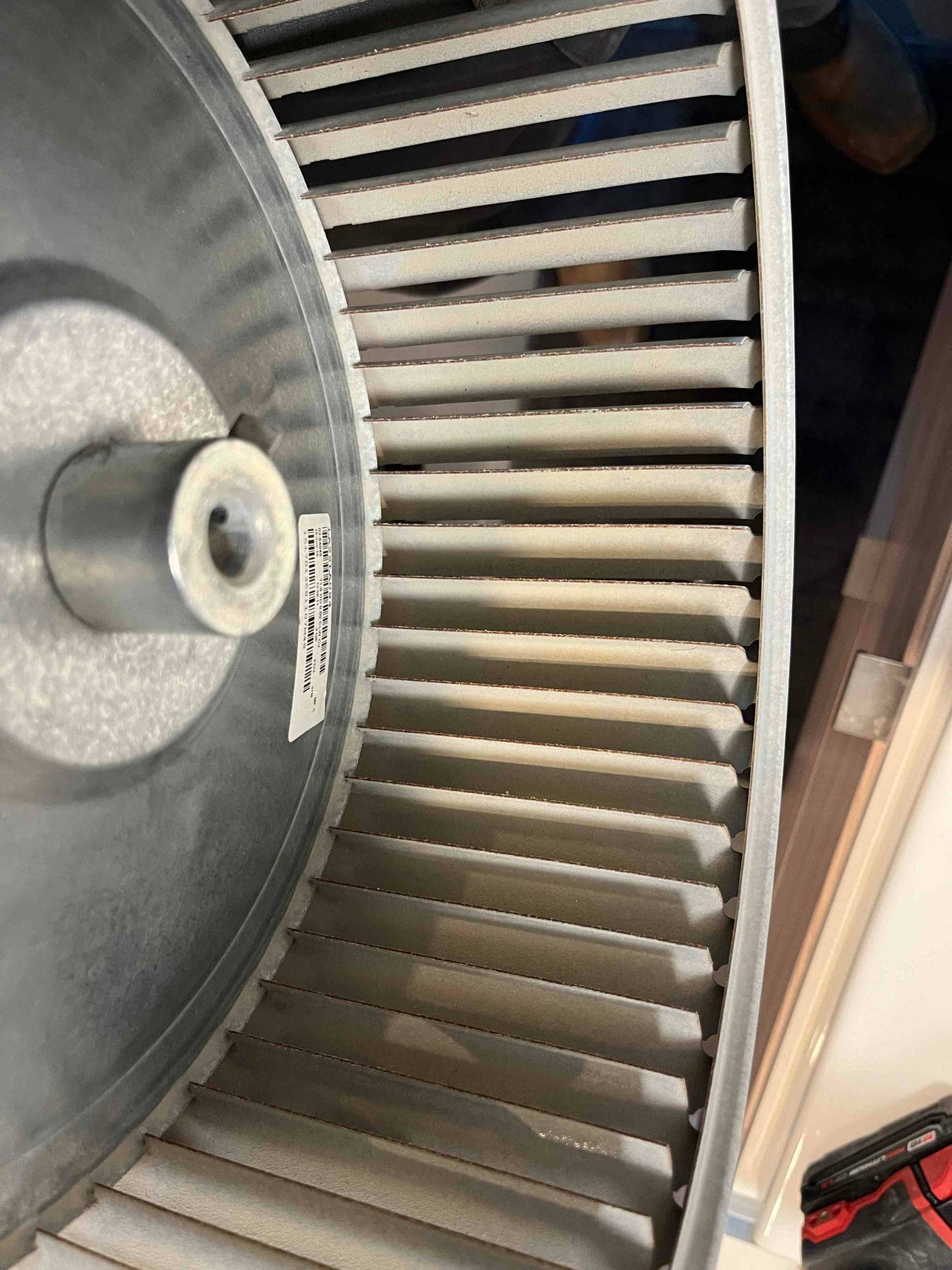 Removed HVAC blower wheel showing metal fins with light dust accumulation on blades and hub.