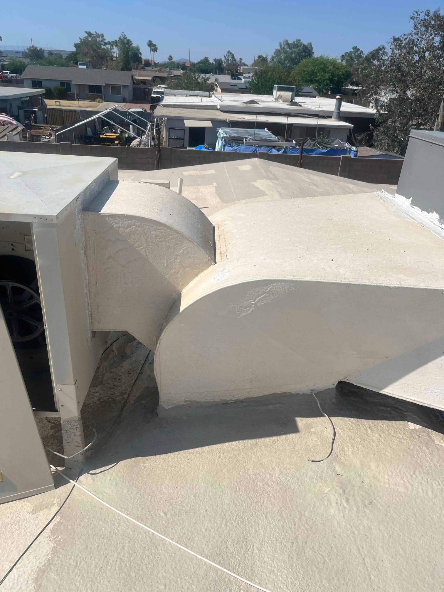Rooftop package unit with exterior duct transitions and sealed roof coating, access panel open at side.