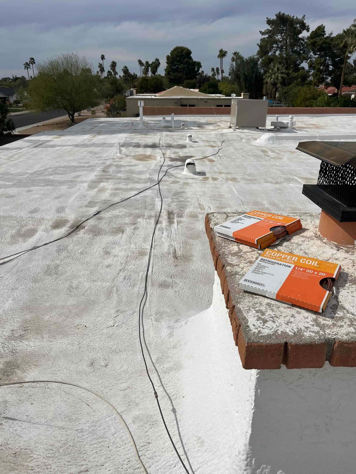 Rooftop packaged unit in background with wiring across roof and copper coil boxes staged at parapet.