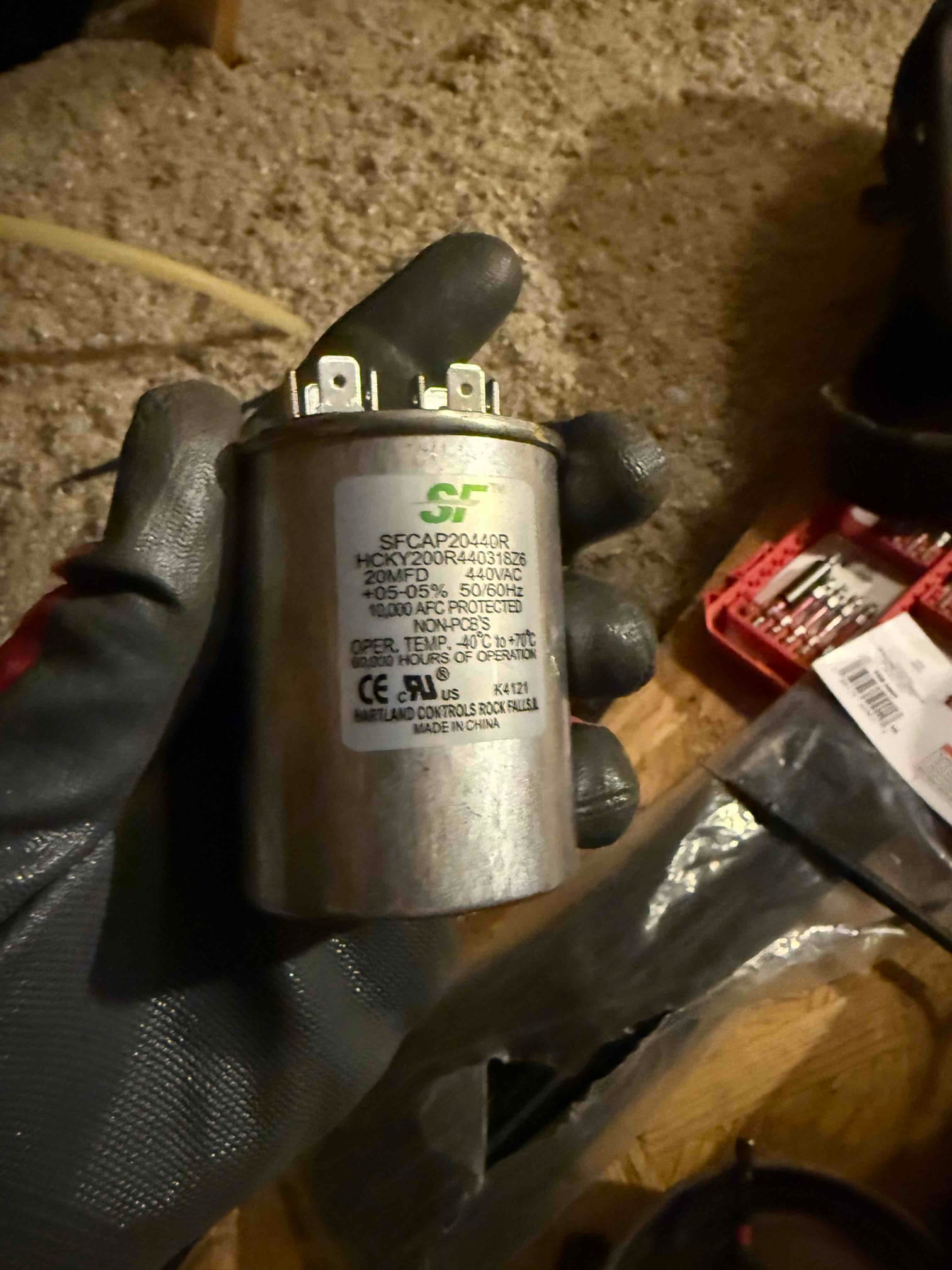 Run capacitor labeled 20 MFD 440 VAC with three terminals, held by a gloved hand.