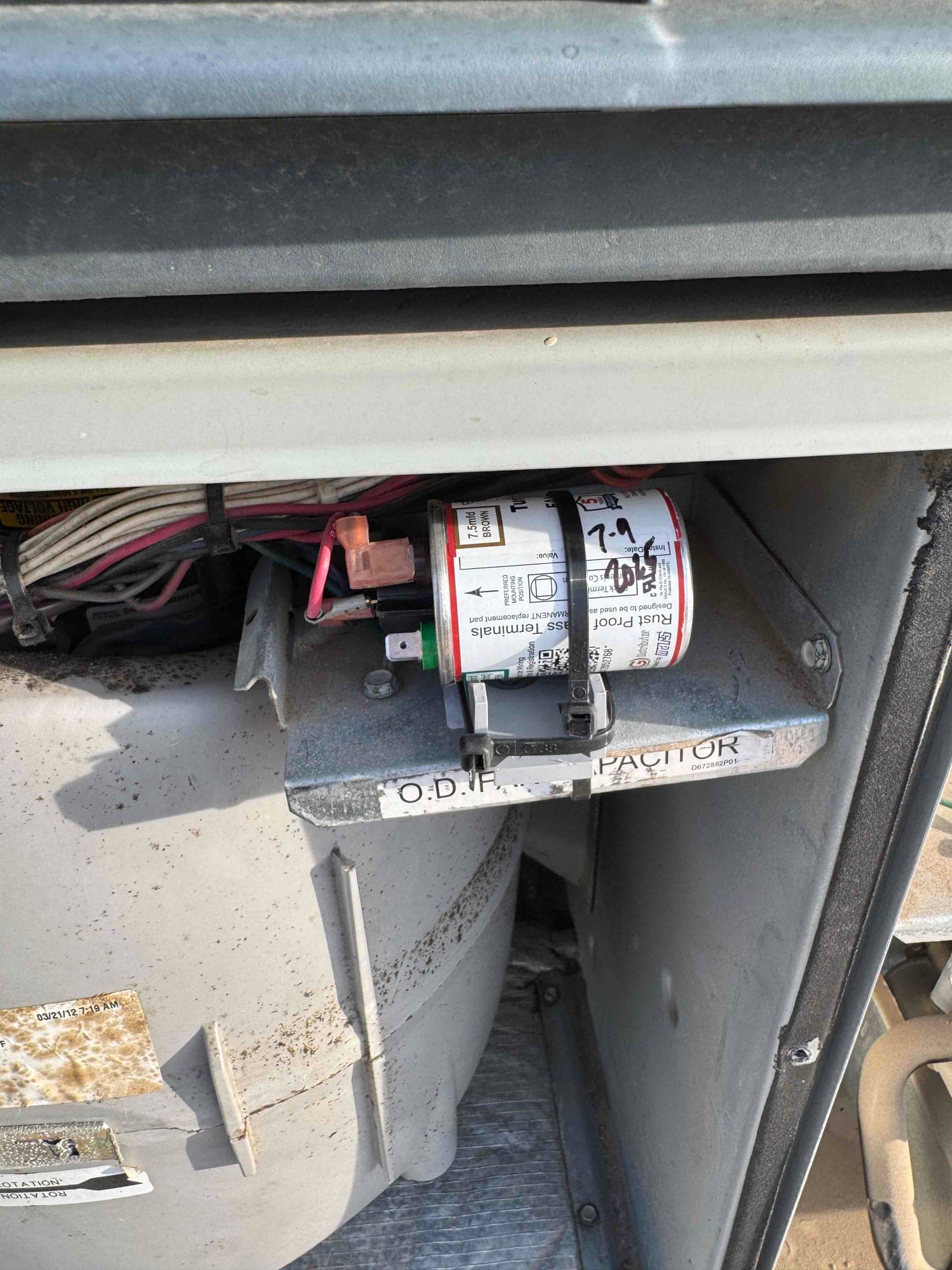 Run capacitor labeled 7.5 μF secured on a bracket with connected wiring inside the outdoor unit.