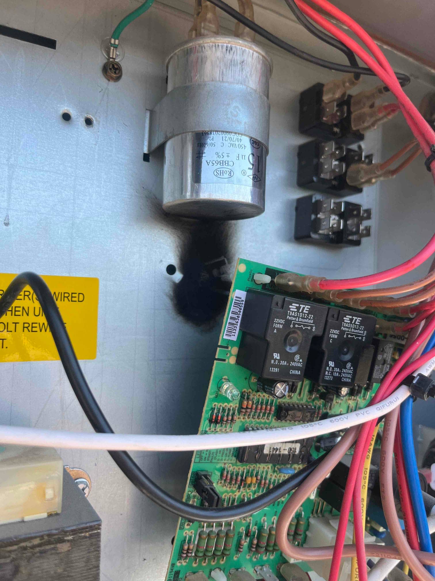 Run capacitor mounted inside control panel with a blackened area on the metal backplate near it.