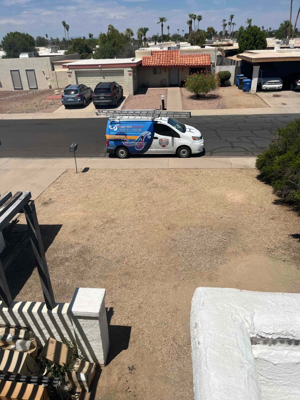 Service van parked on a residential street in front of the home, with a ladder on the roof rack.