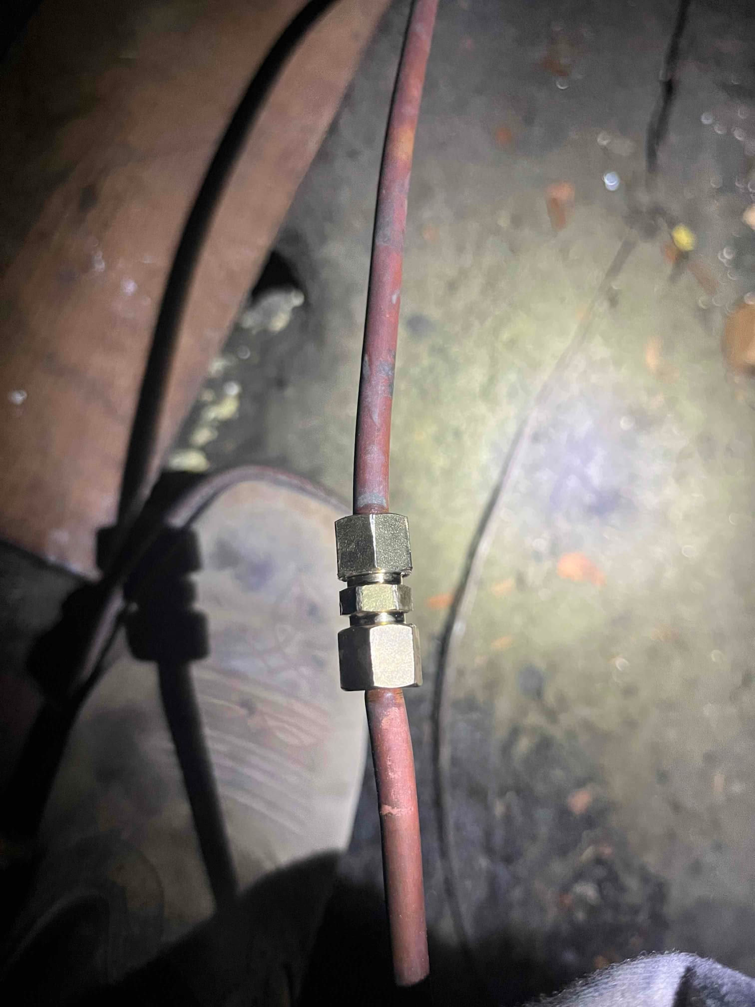 Small-diameter copper tubing with a brass compression union joining two sections, photographed during HVAC service.
