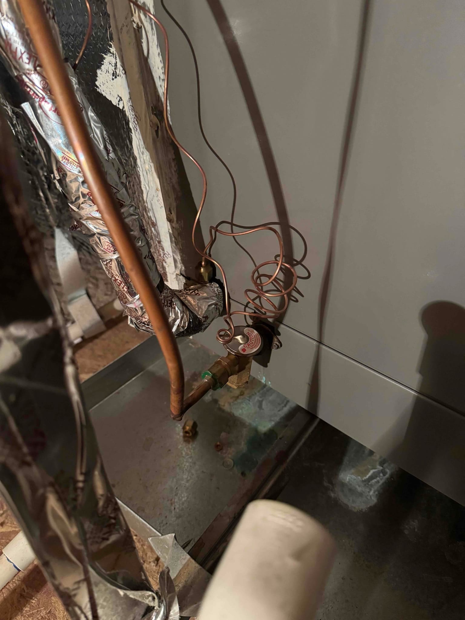 Thermal expansion valve with copper refrigerant lines entering an air handler above the drain pan.