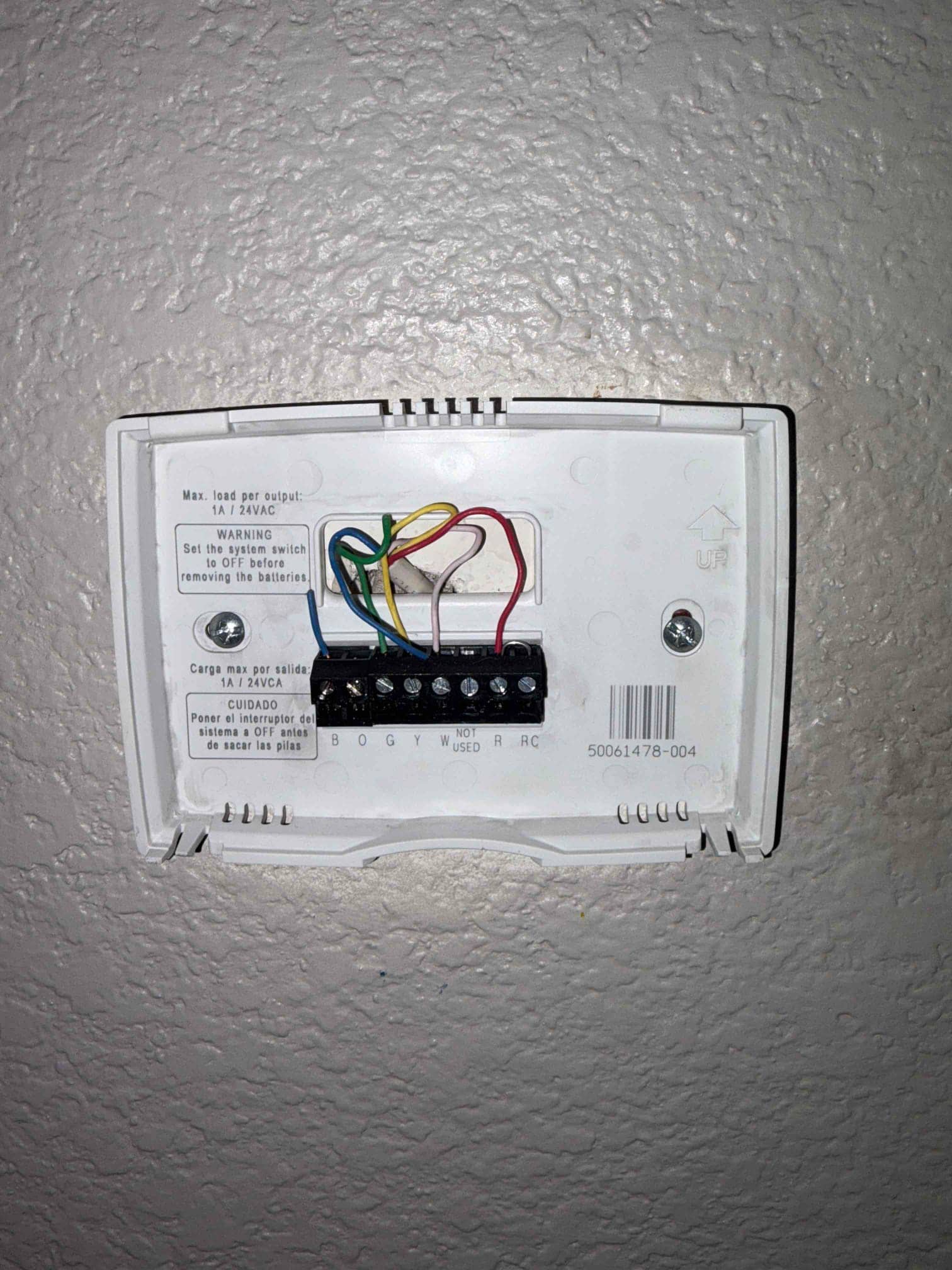 Thermostat wall plate with labeled terminals B O G Y W R RC and connected control wires secured to screws.