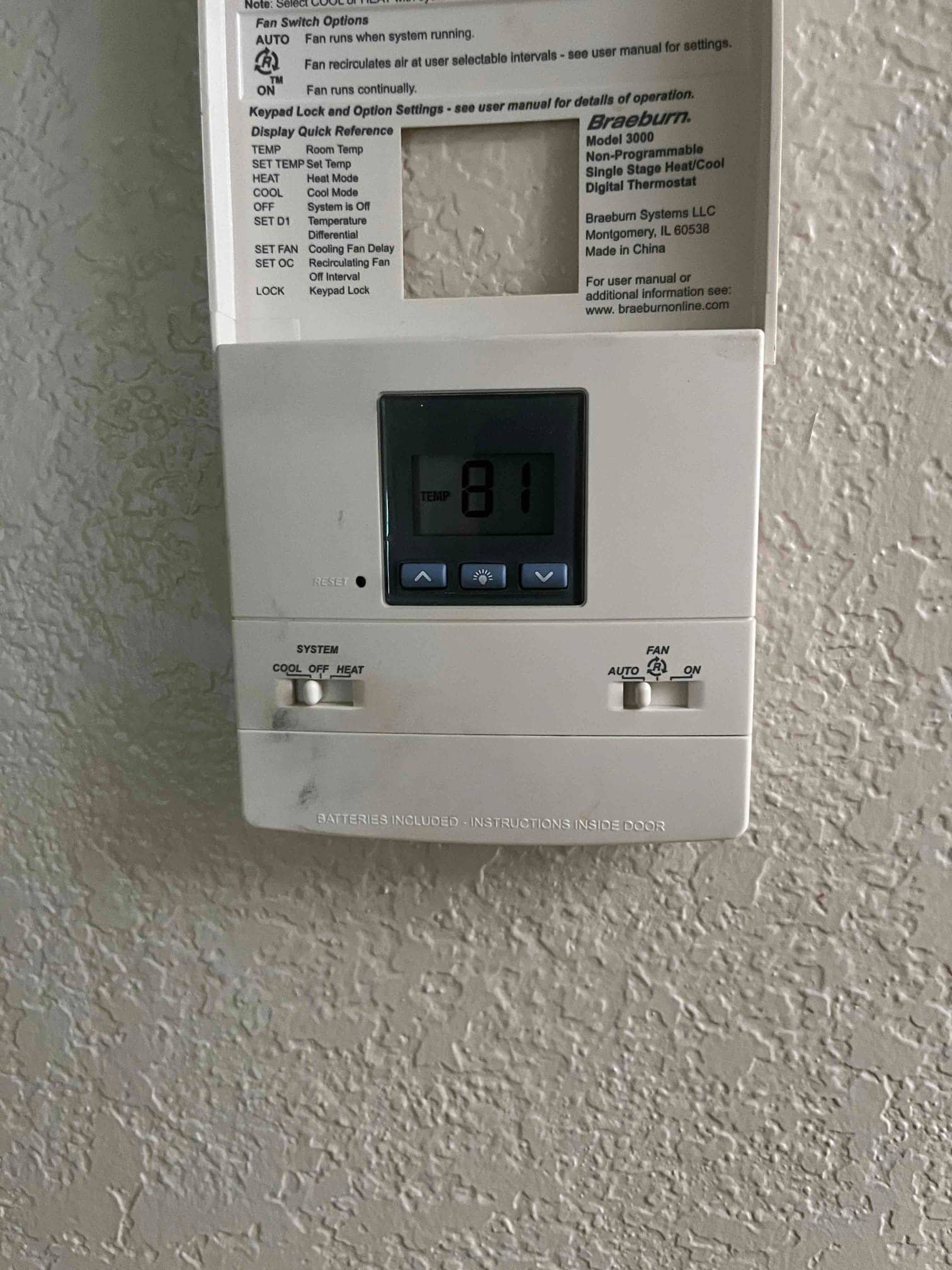 Wall-mounted digital thermostat with cover open, showing 81 temperature reading and system and fan selector switches.