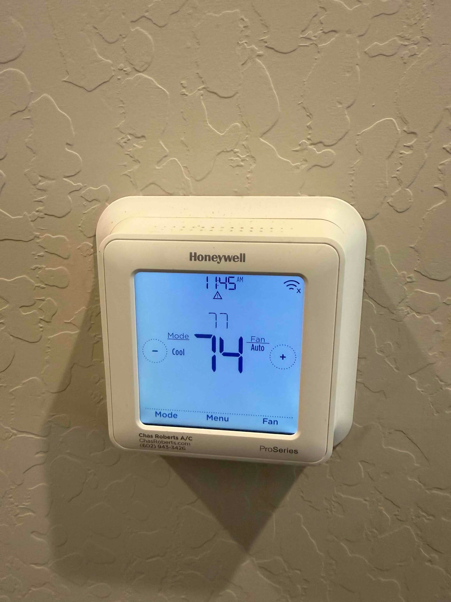 Wall-mounted digital thermostat display shows 74 degrees with system in Cool mode and the fan set to Auto.