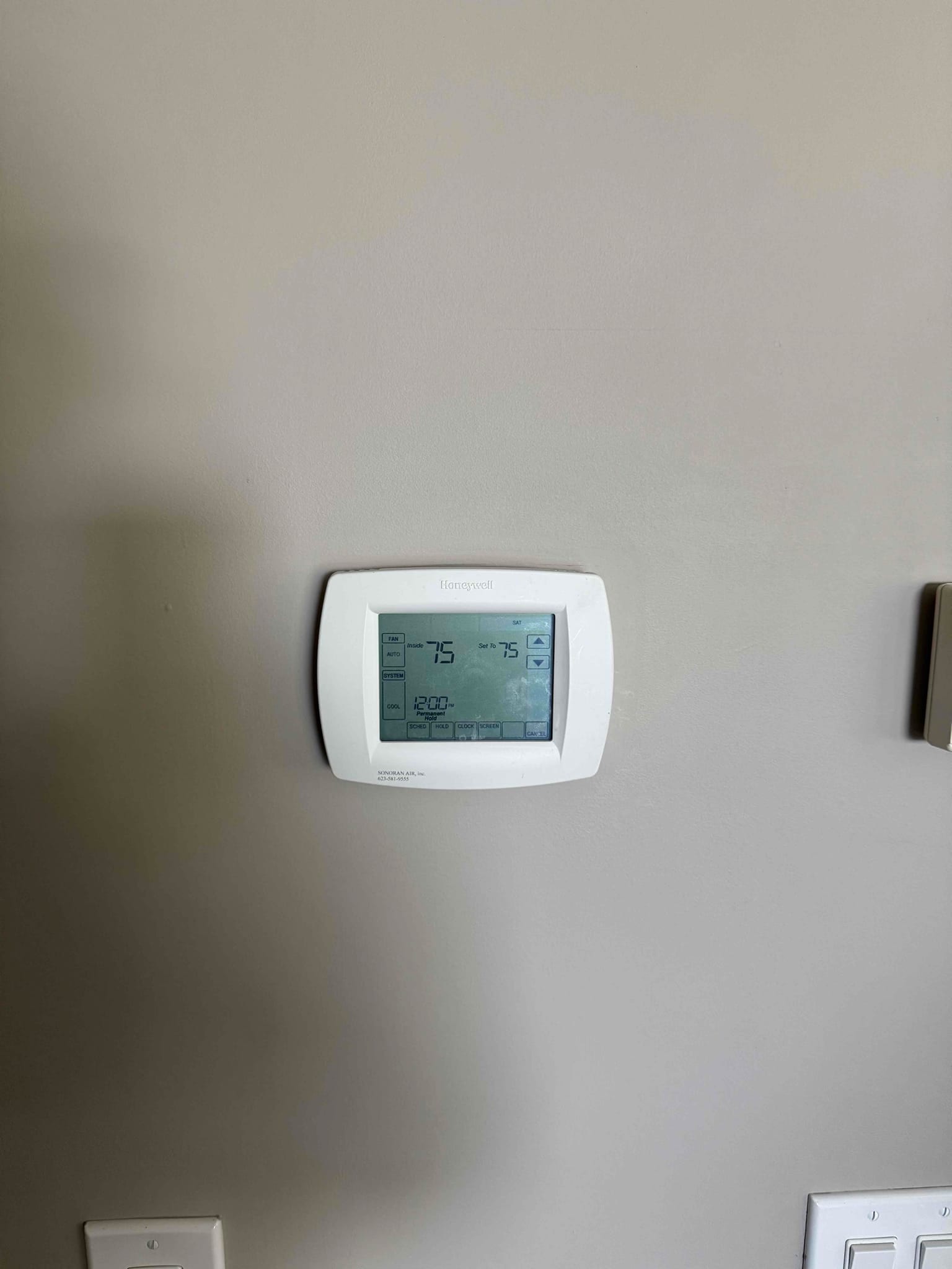 Wall-mounted digital thermostat displays 75 degrees current temperature with setpoint 75 and cooling mode selected.