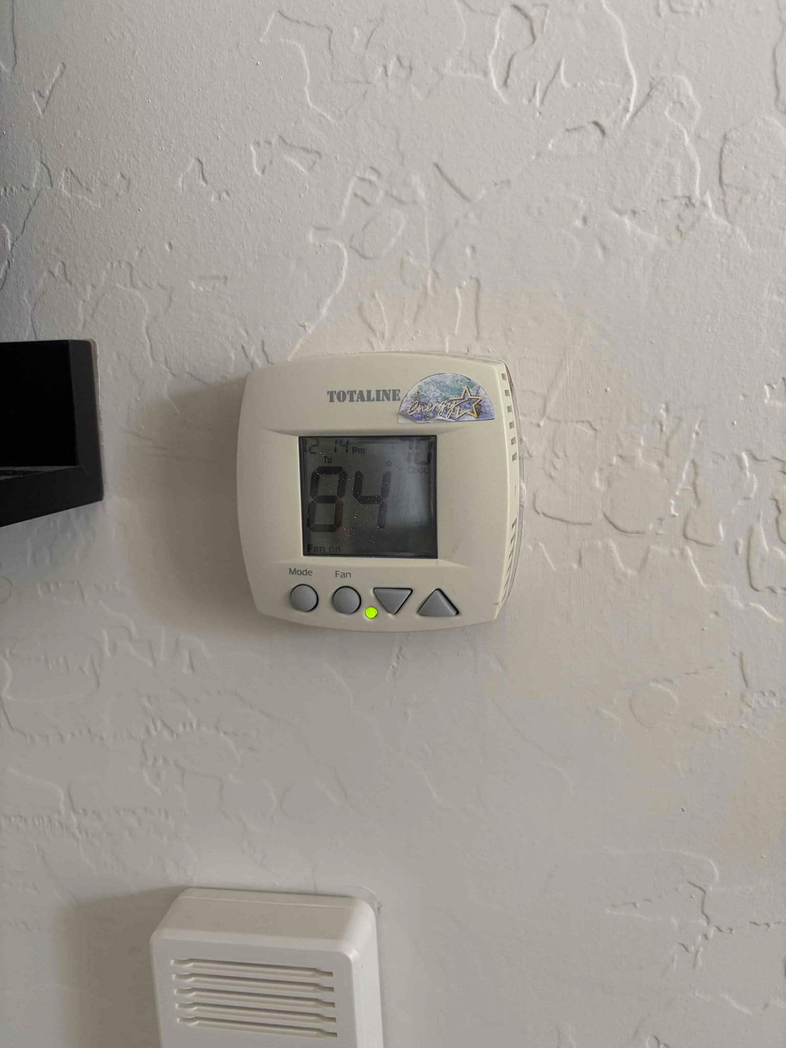 Wall-mounted digital thermostat displays 84 with fan indicator lit and control buttons for mode and fan.