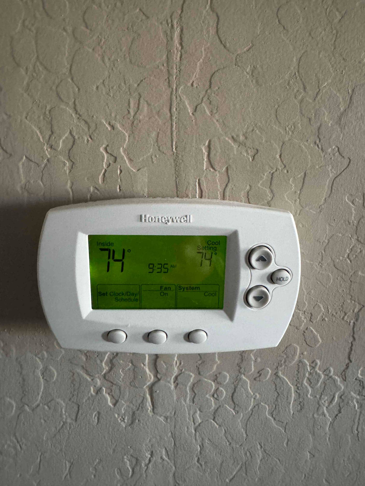 Wall-mounted digital thermostat displays inside 74 with cooling setpoint at 74 and fan switch in On.