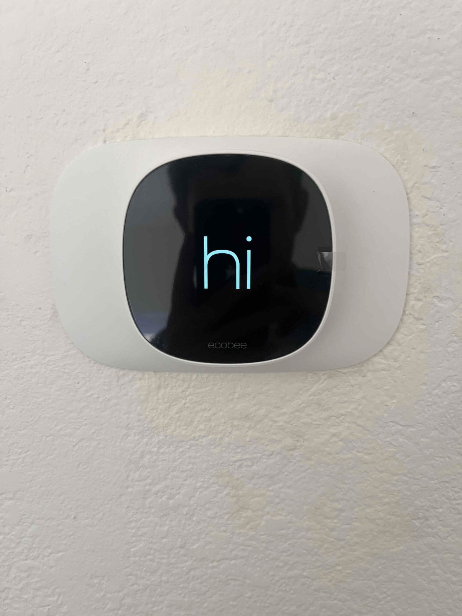 Wall-mounted digital thermostat powers on, showing a welcome screen with the word hi on its display.