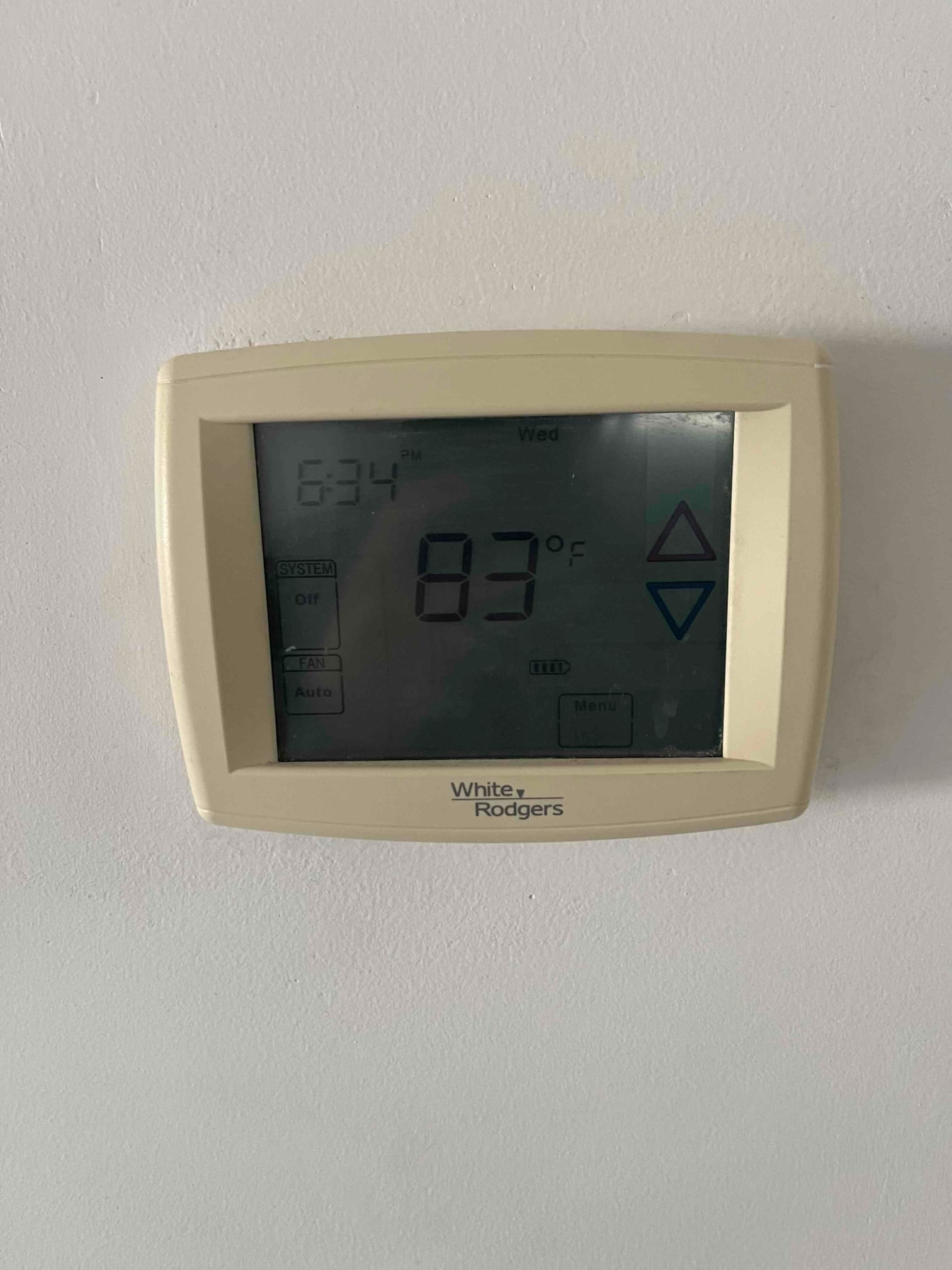 Wall-mounted thermostat display shows 83°F room temperature with system and fan control indicators visible.