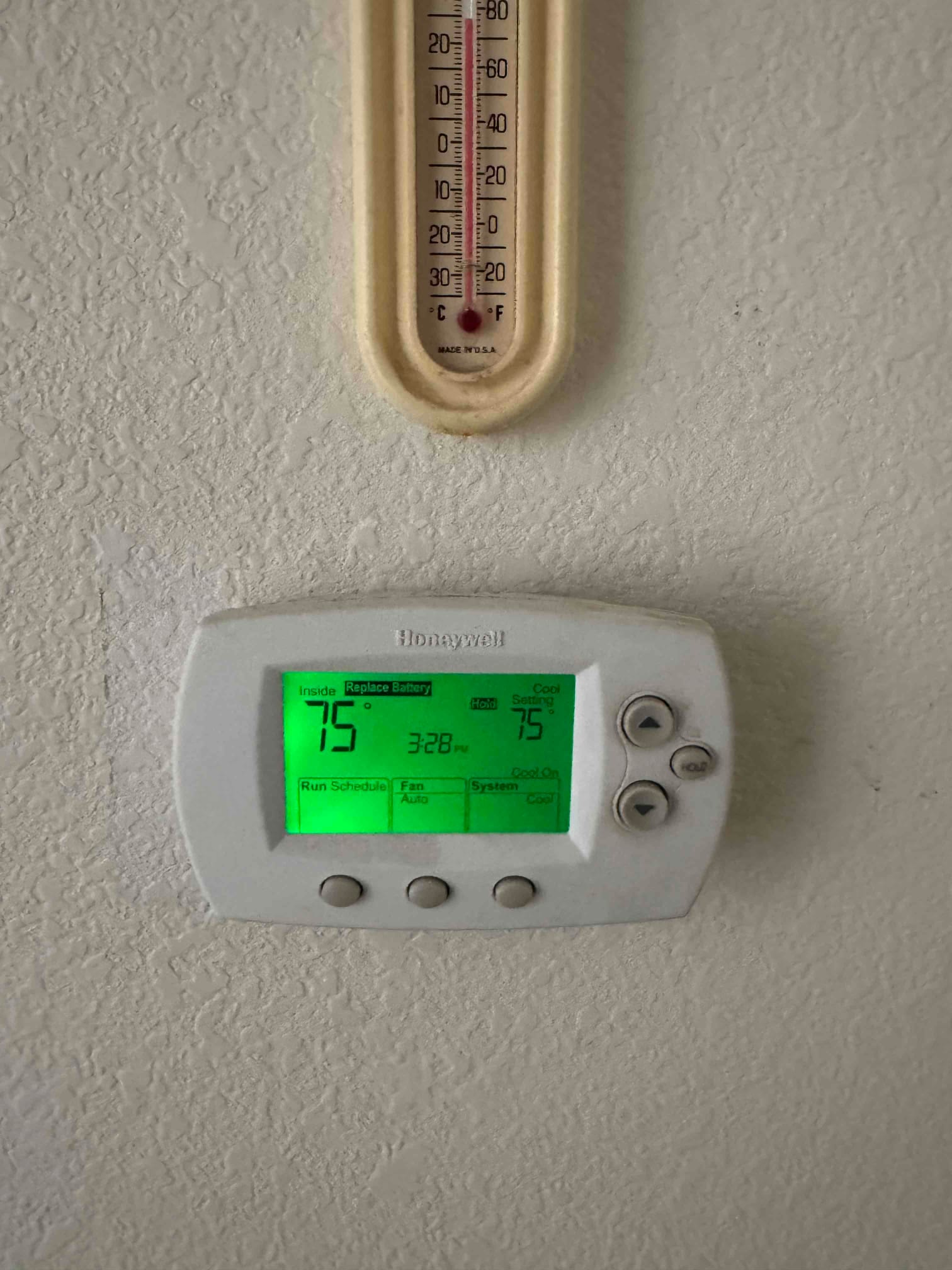 Wall-mounted thermostat displays inside 75°F and cool setting 75°F at 3:28 PM, with adjacent analog wall thermometer above.