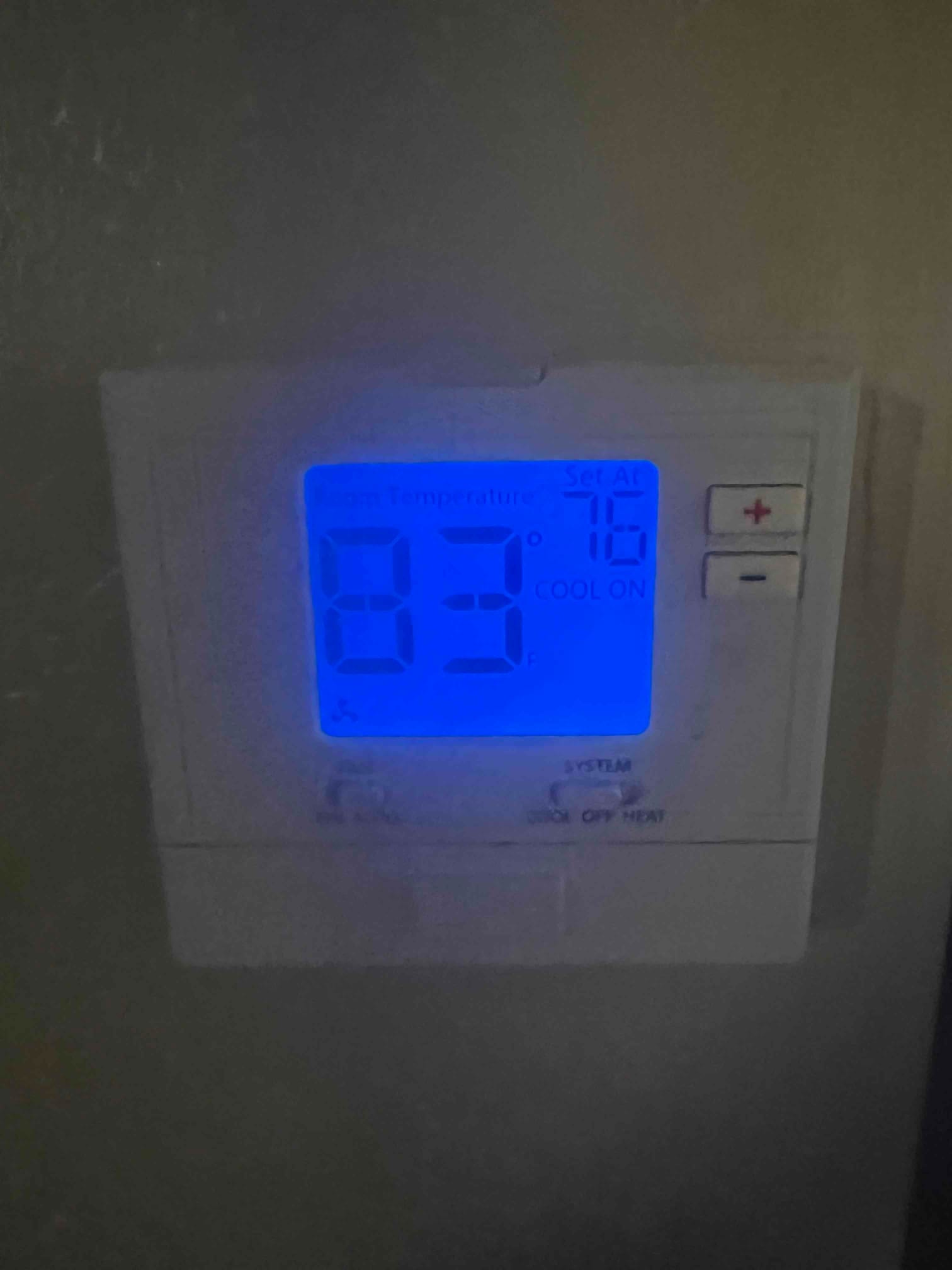 Wall-mounted thermostat displays room temperature 83°F with system set to 75°F and cooling mode on.