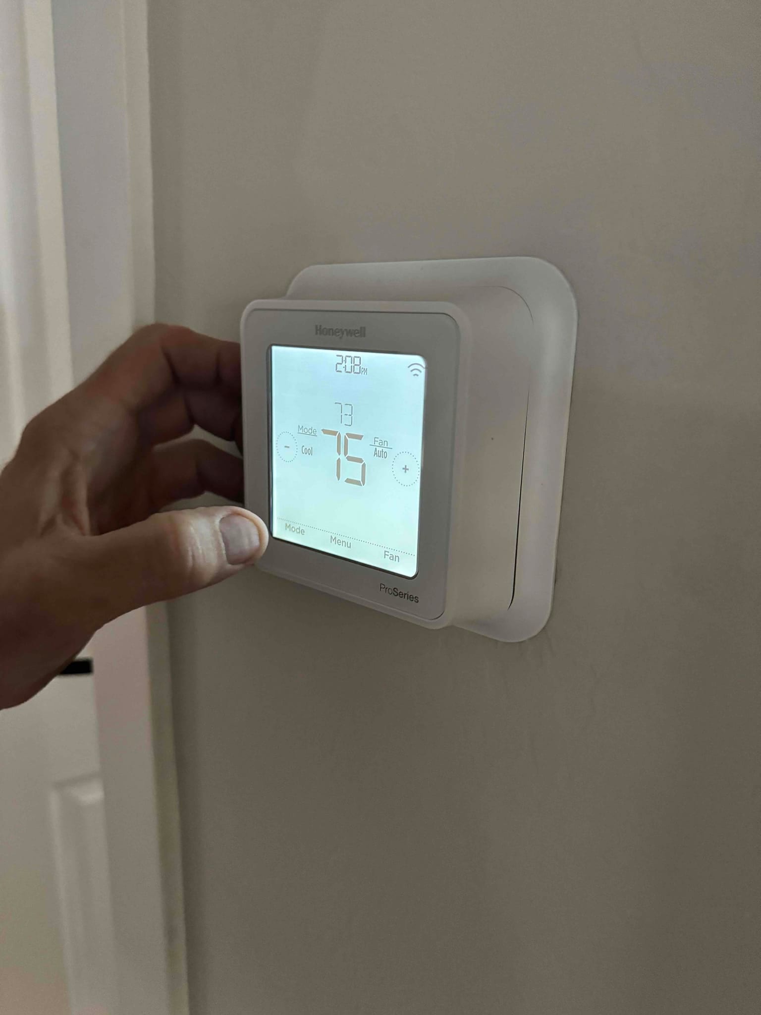 Wall-mounted thermostat set to 75 with indoor temperature 73, mode Cool selected, fan Auto.
