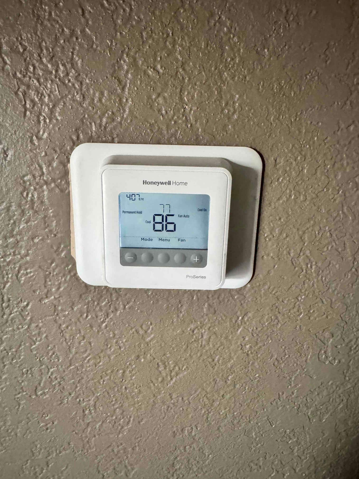 Wall-mounted thermostat shows 86°F indoor temperature, cool setpoint 77°F, fan Auto, Cool On indicator lit.