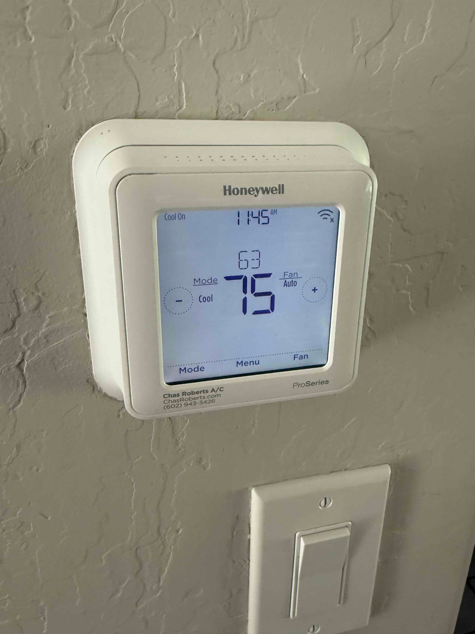 Wall-mounted thermostat shows Cool On, 75 setpoint, 63 indoor temperature, fan set to Auto.