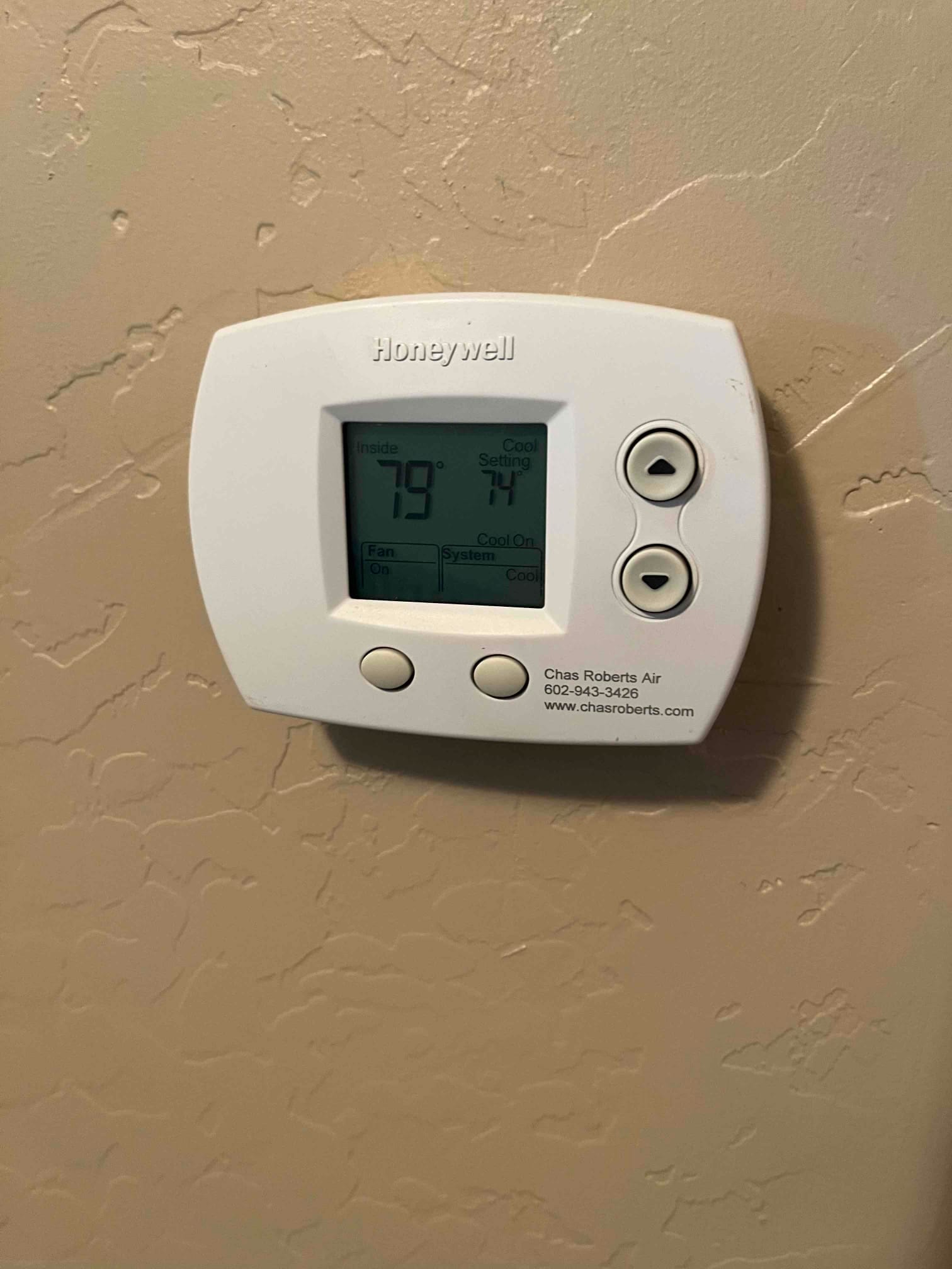 Wall-mounted thermostat shows inside 79°F with cooling set to 74°F, fan on, system cool on.