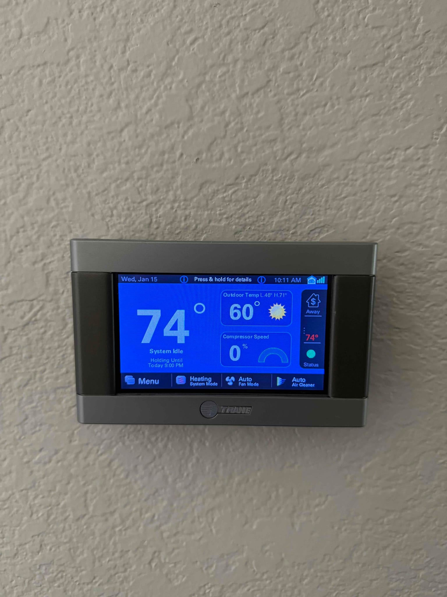 Wall-mounted touchscreen thermostat displays 74°F indoor temperature, 60°F outdoor temperature, system idle status, and compressor speed at 0%.