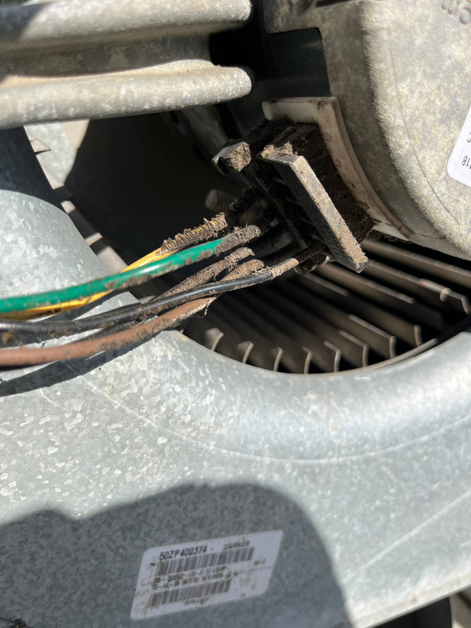 Wiring harness connector at an outdoor condenser fan motor with accumulated dirt on the plug.