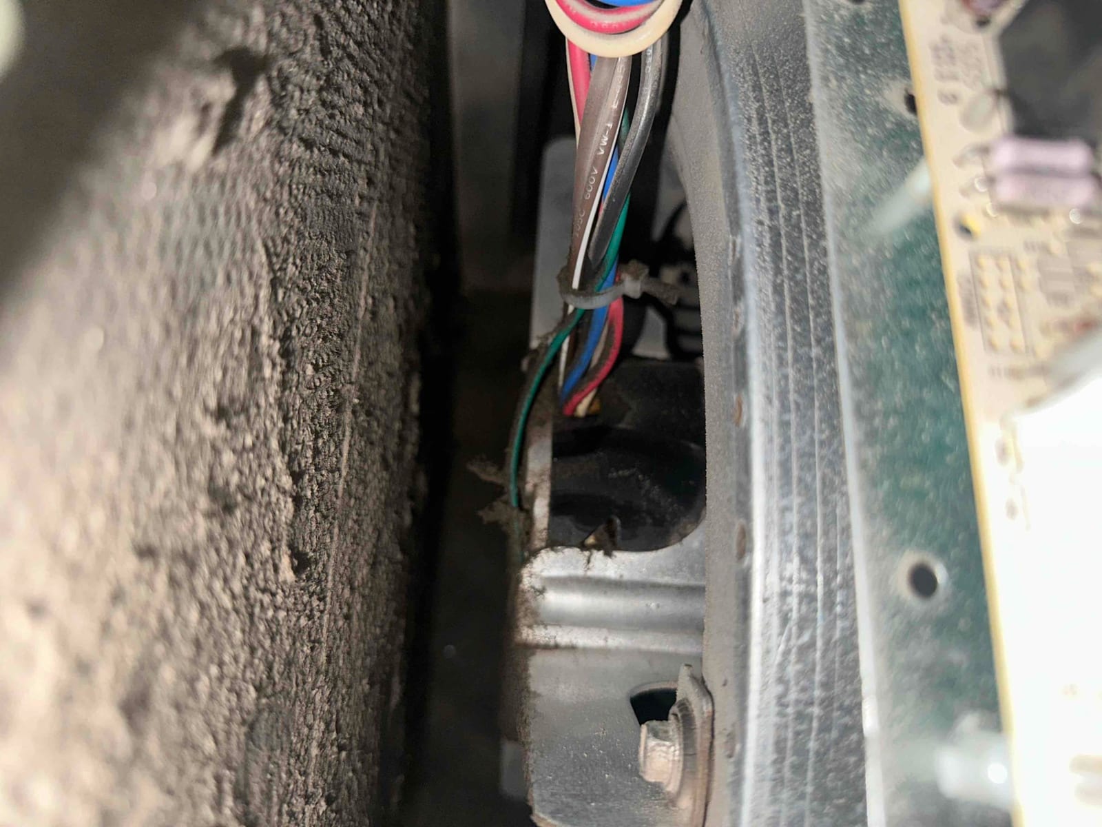 Wiring harness and control board inside air handler cabinet, with heavy dust buildup on adjacent surface and components.