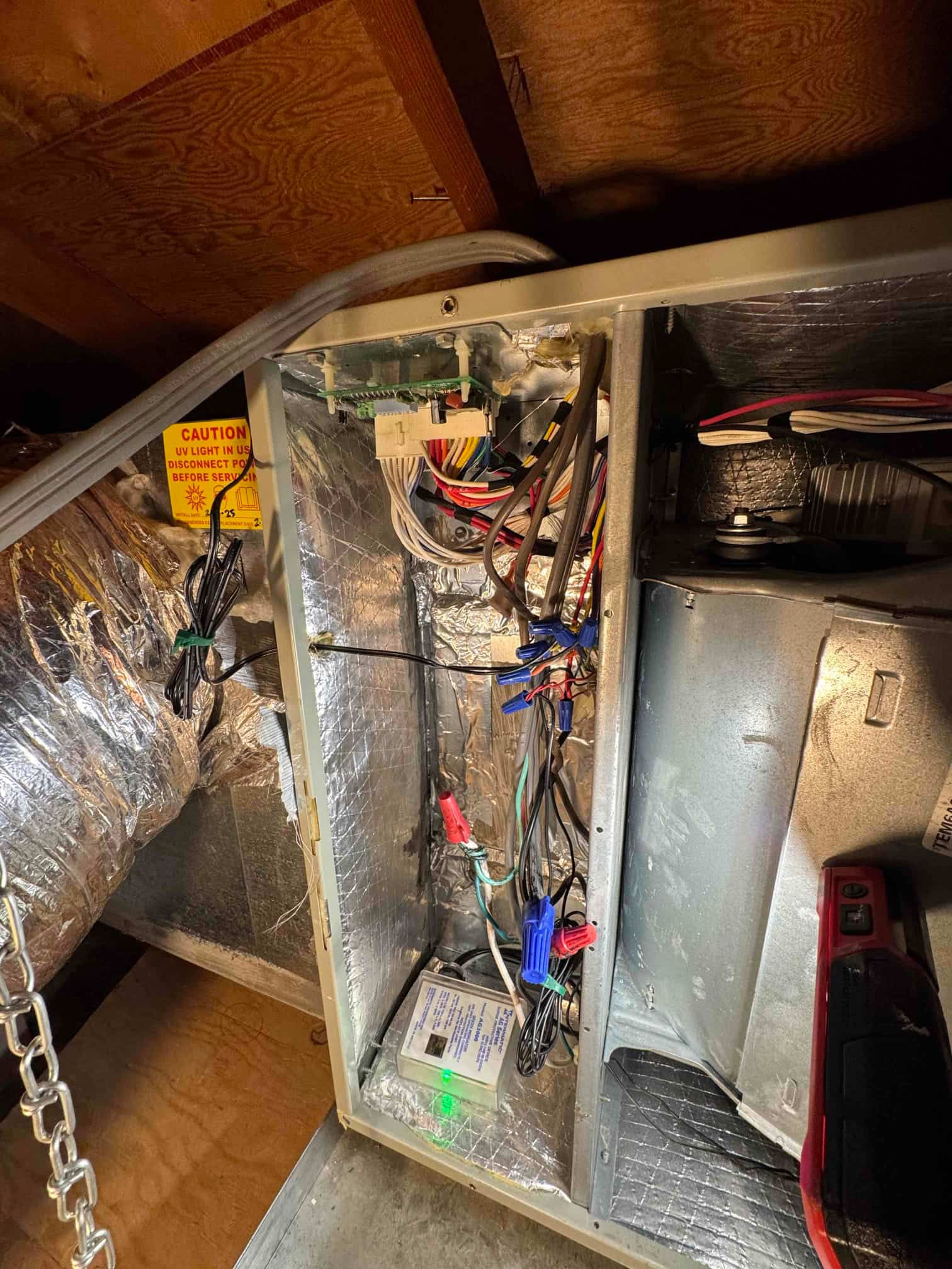 Air handler electrical compartment open, showing wiring connections, caution label, and control module with green indicator illuminated.
