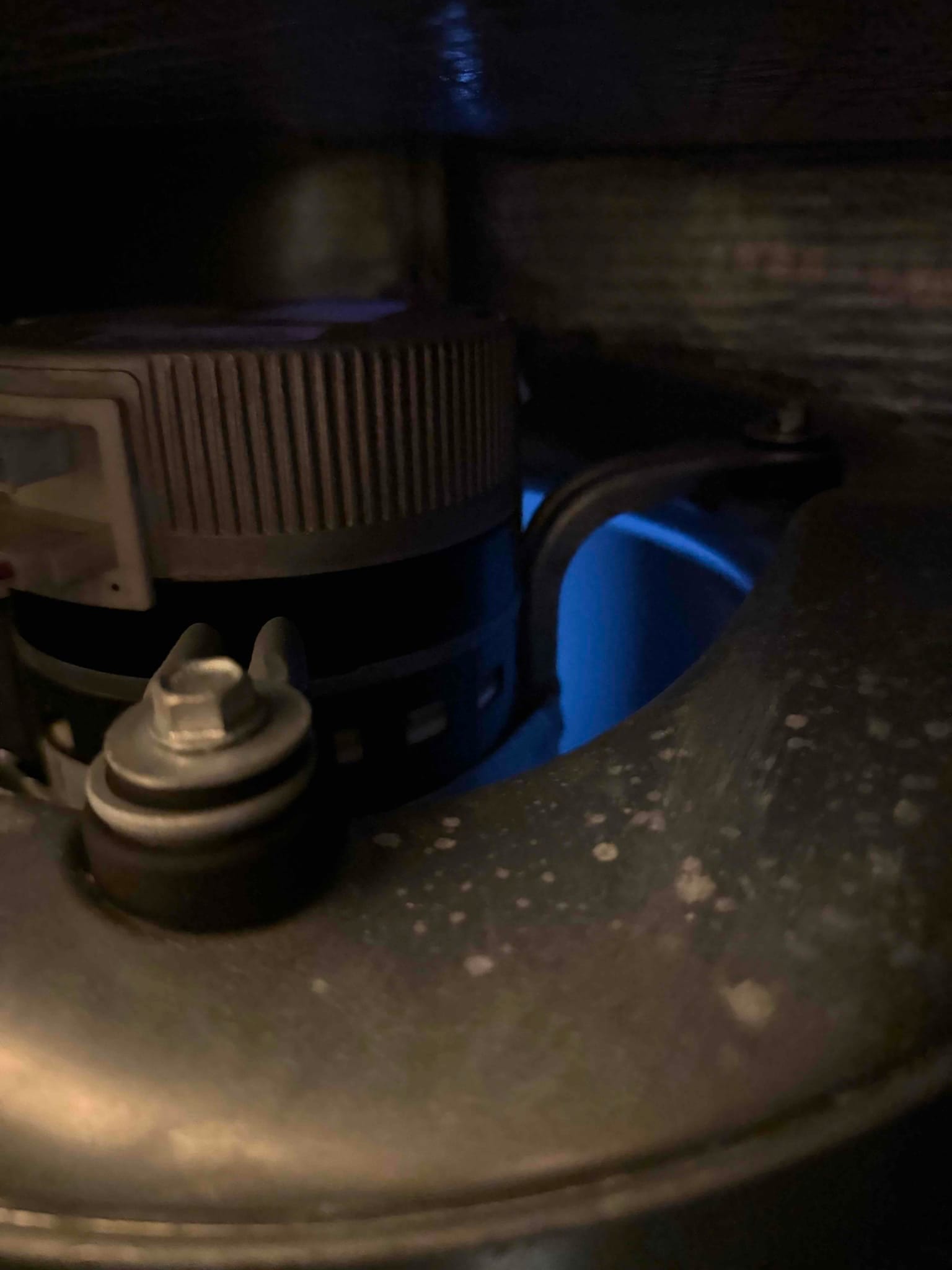 Blue burner flame visible inside a gas furnace, with the draft inducer motor and housing in the foreground.