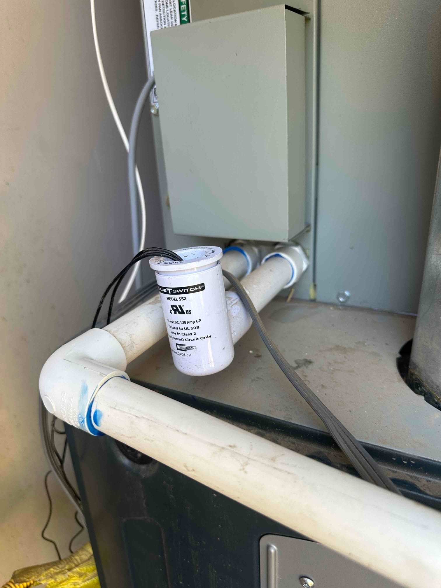 Condensate float switch mounted on the drain line at the air handler, with PVC fittings and wiring visible.