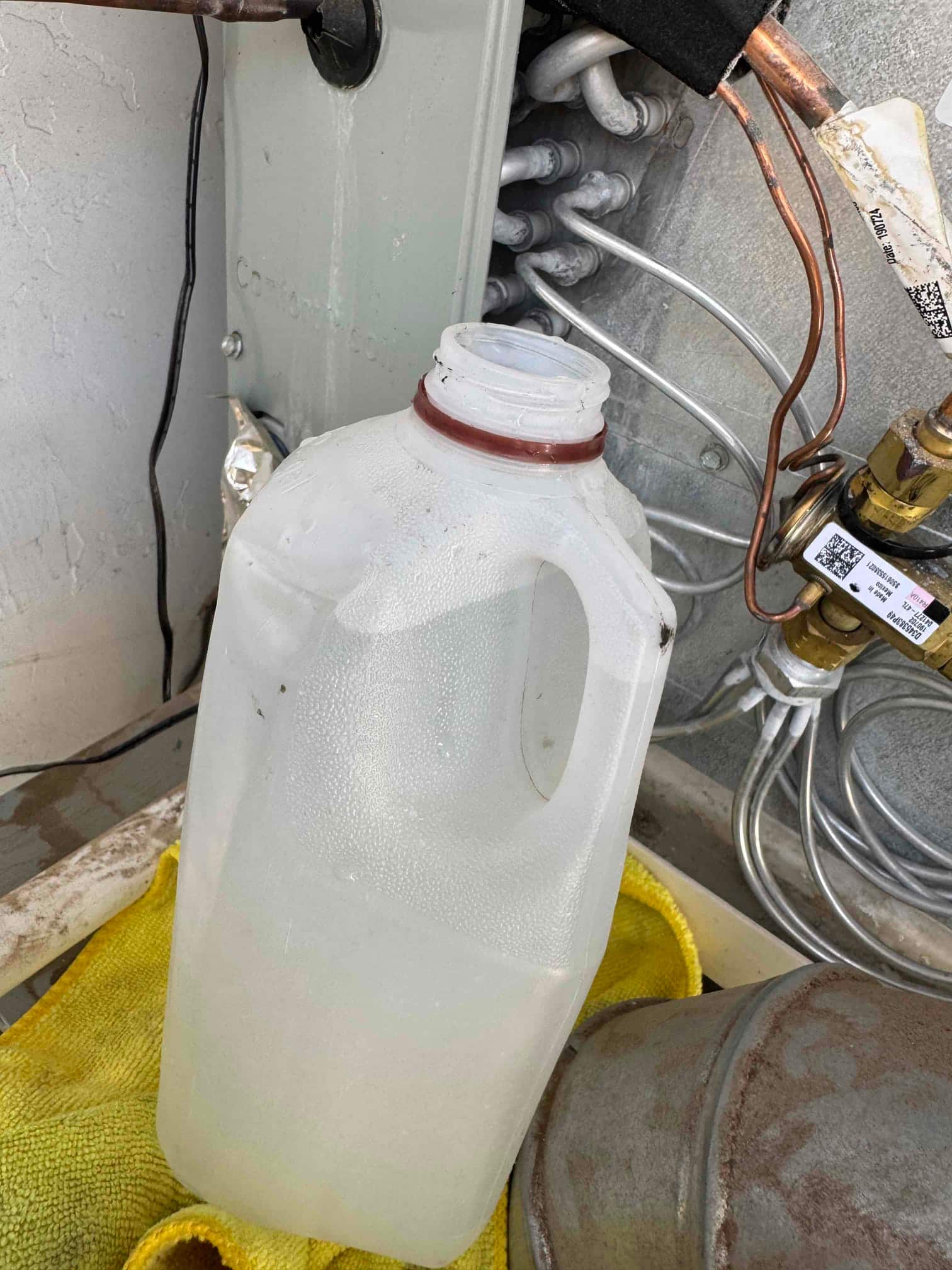 Copper refrigerant lines and aluminum coil connections inside an HVAC cabinet, with barcode labels on components and surrounding service area.