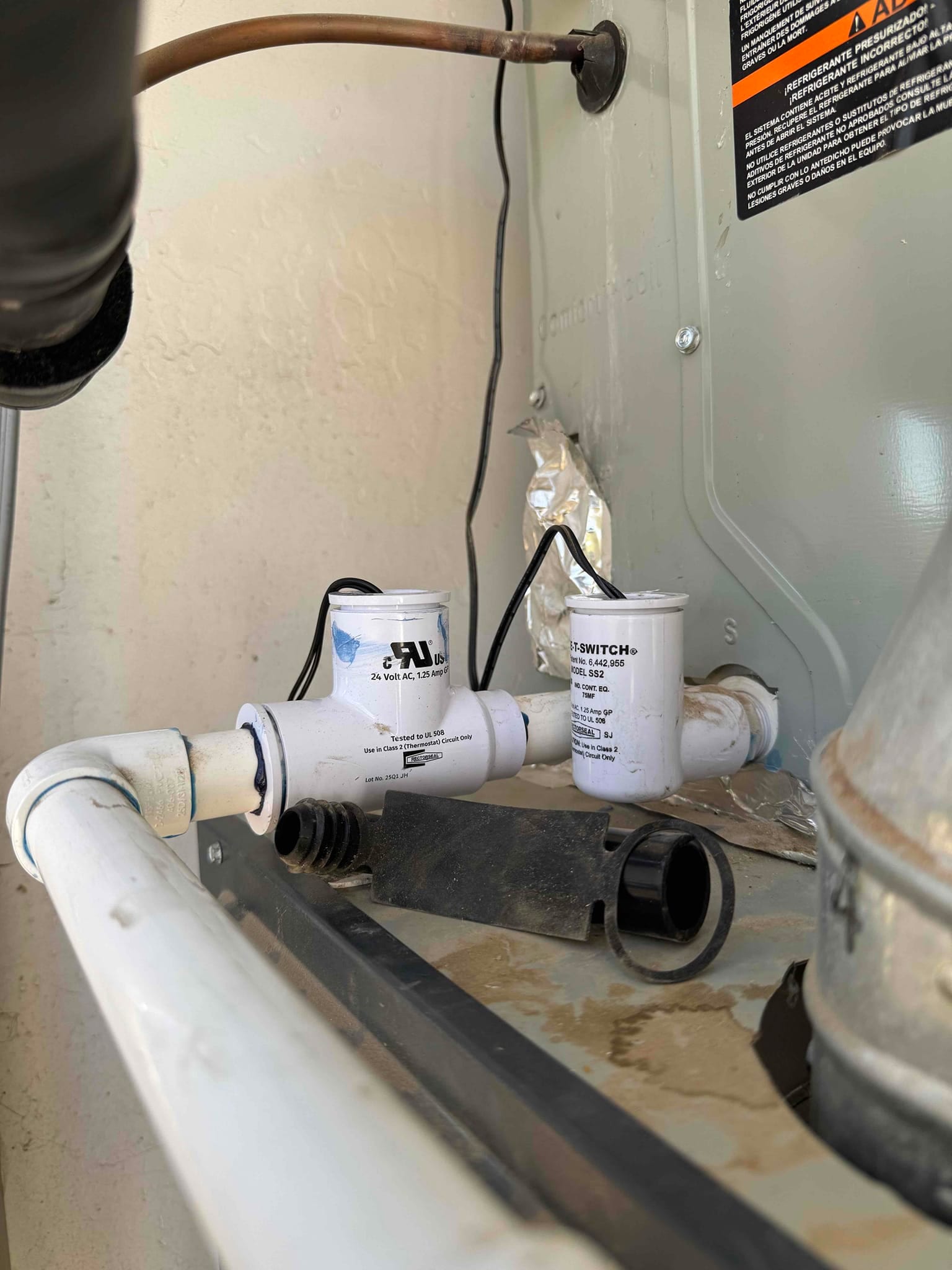 Drain pan shows dirt and moisture near PVC condensate drain with two float switches and connected wiring.