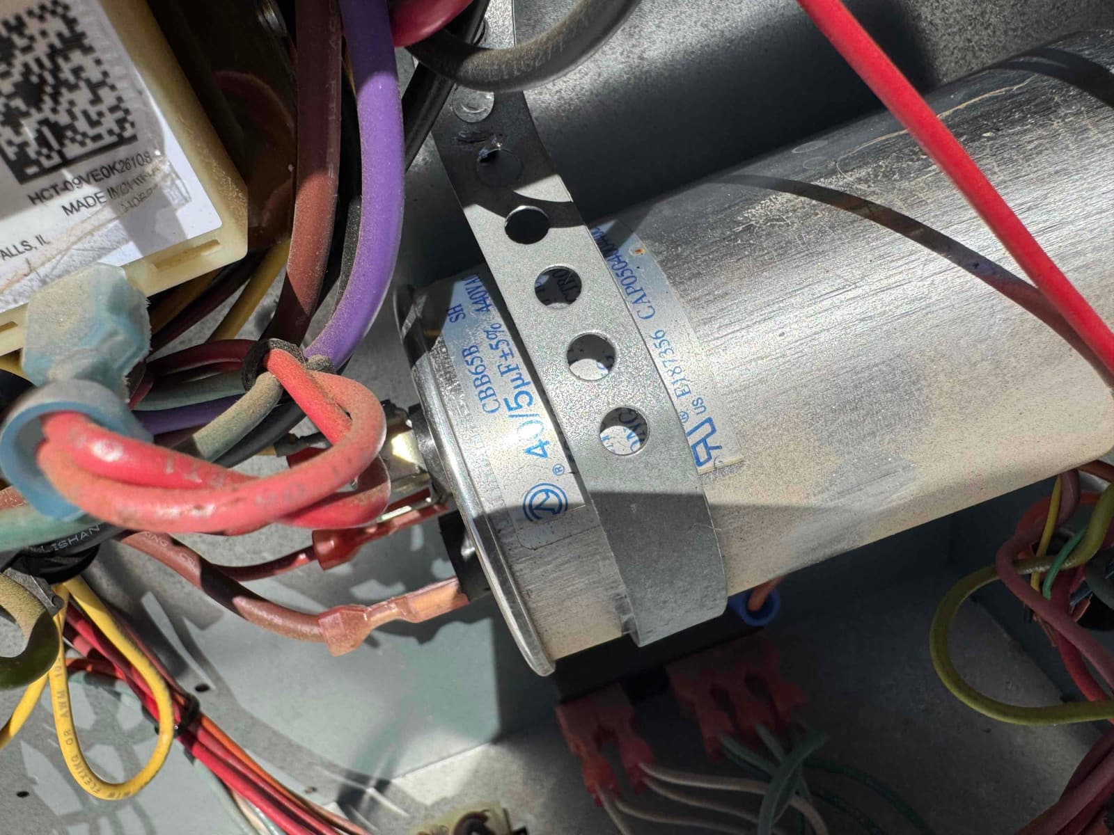 Dual-run capacitor labeled 45/5 μF, mounted in a bracket with multiple wires connected to its terminals.