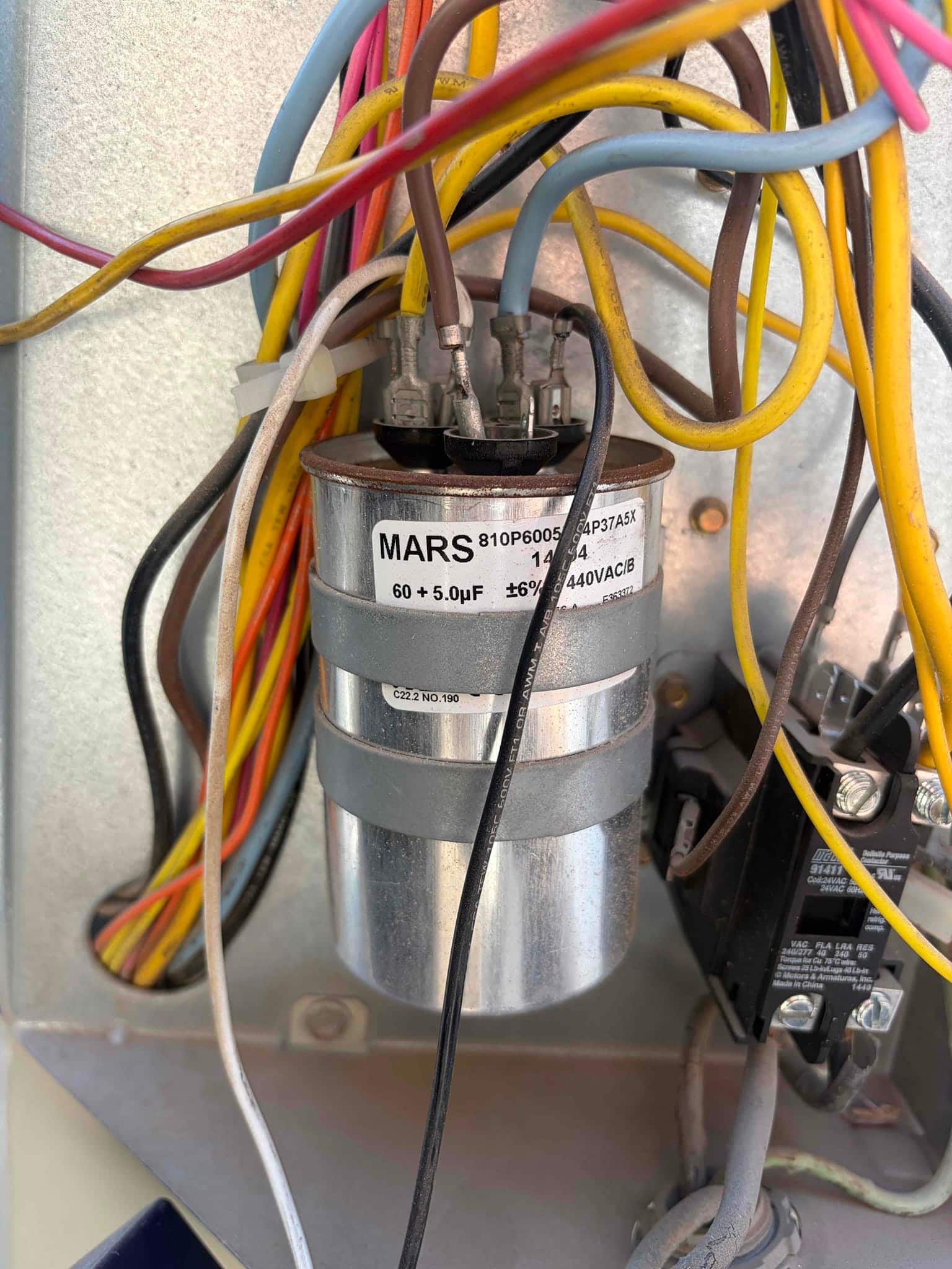 Dual-run capacitor labeled 60 + 5.0 μF, 440VAC, with multiple colored wires connected to its terminals beside the contactor.