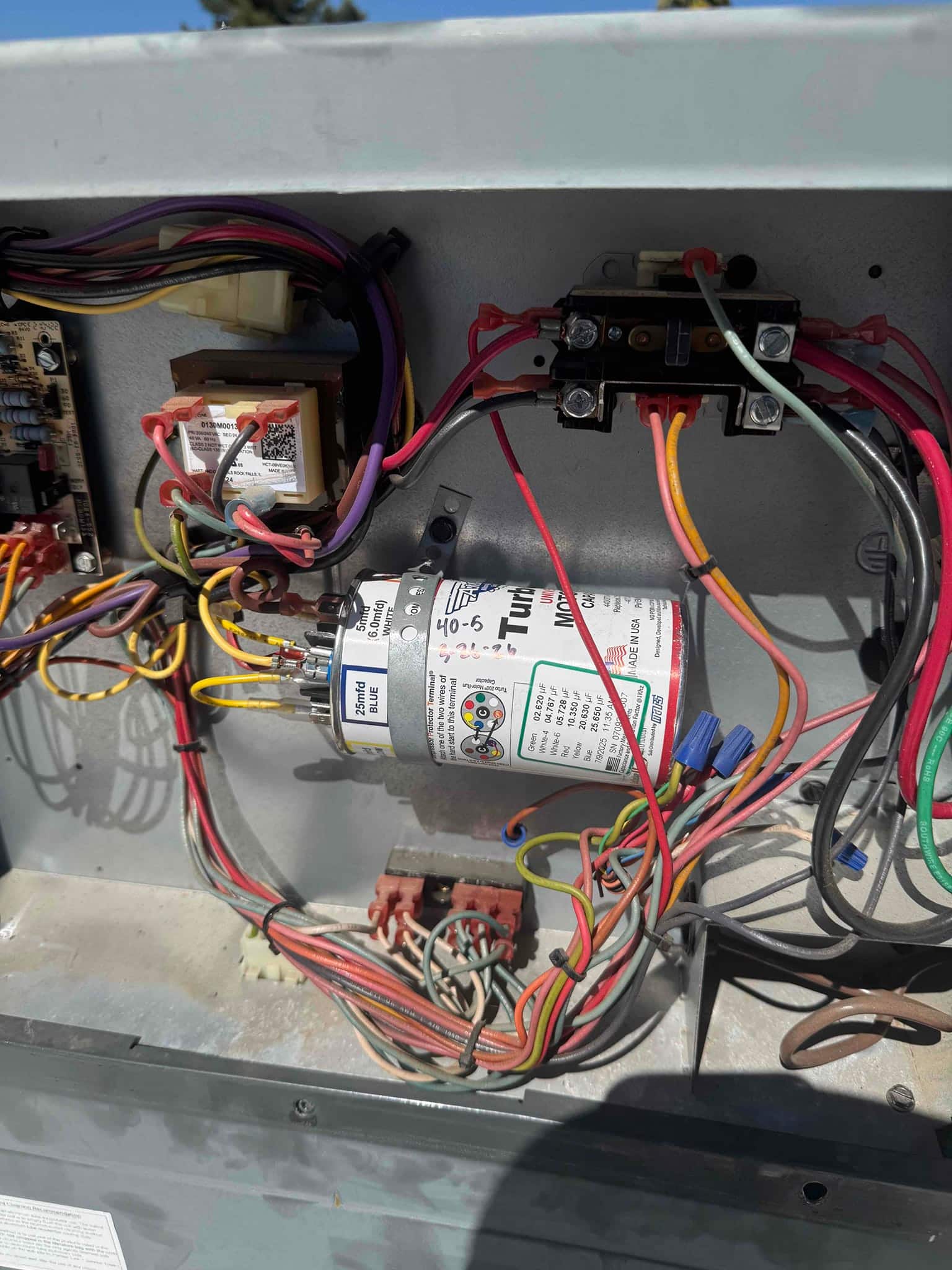 Dual-run capacitor mounted in the condenser control compartment with multiple wires connected to its labeled terminals.
