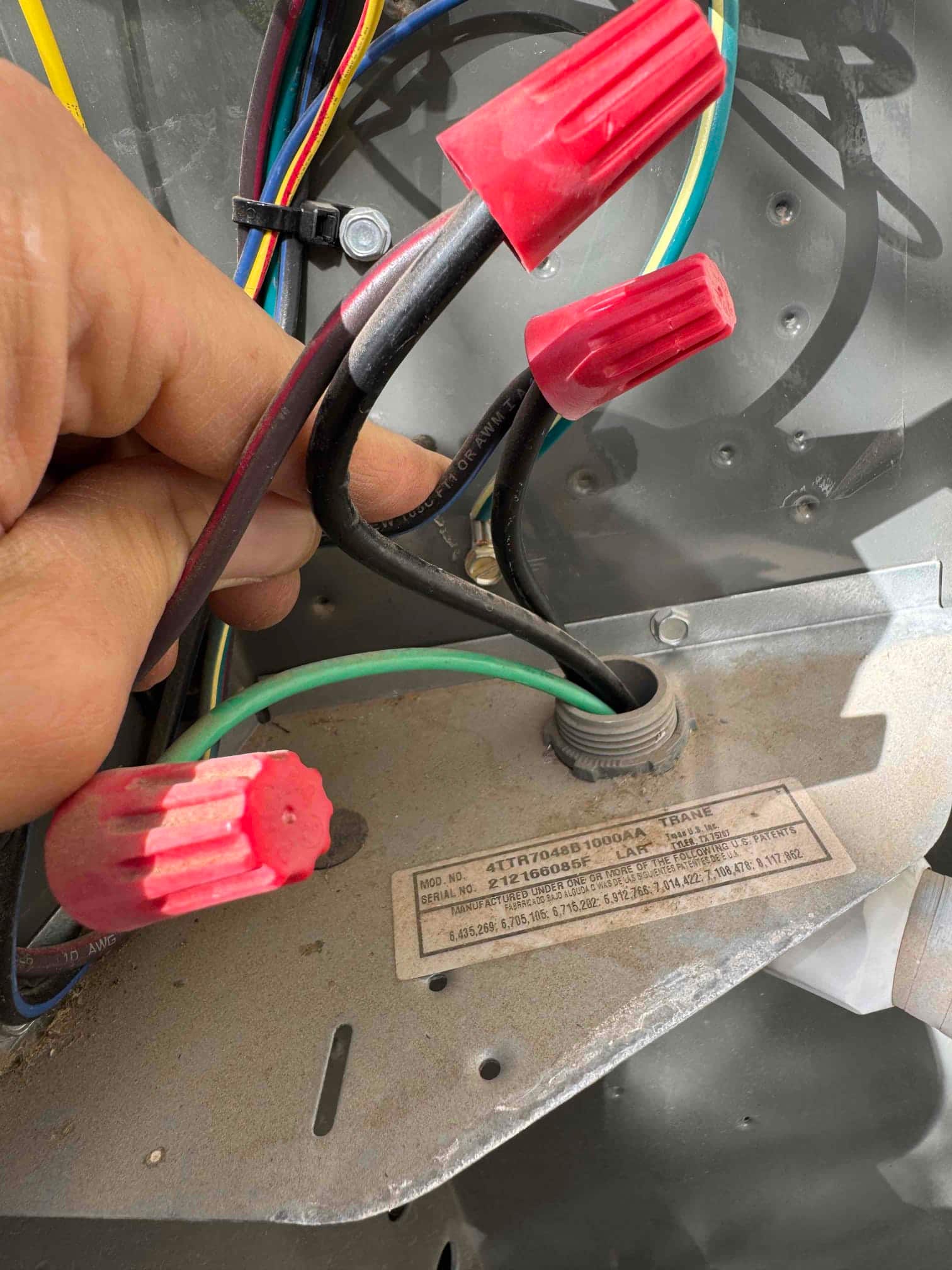 Electrical compartment shows multiple conductors with red wire nuts and a green ground passing through a strain relief.