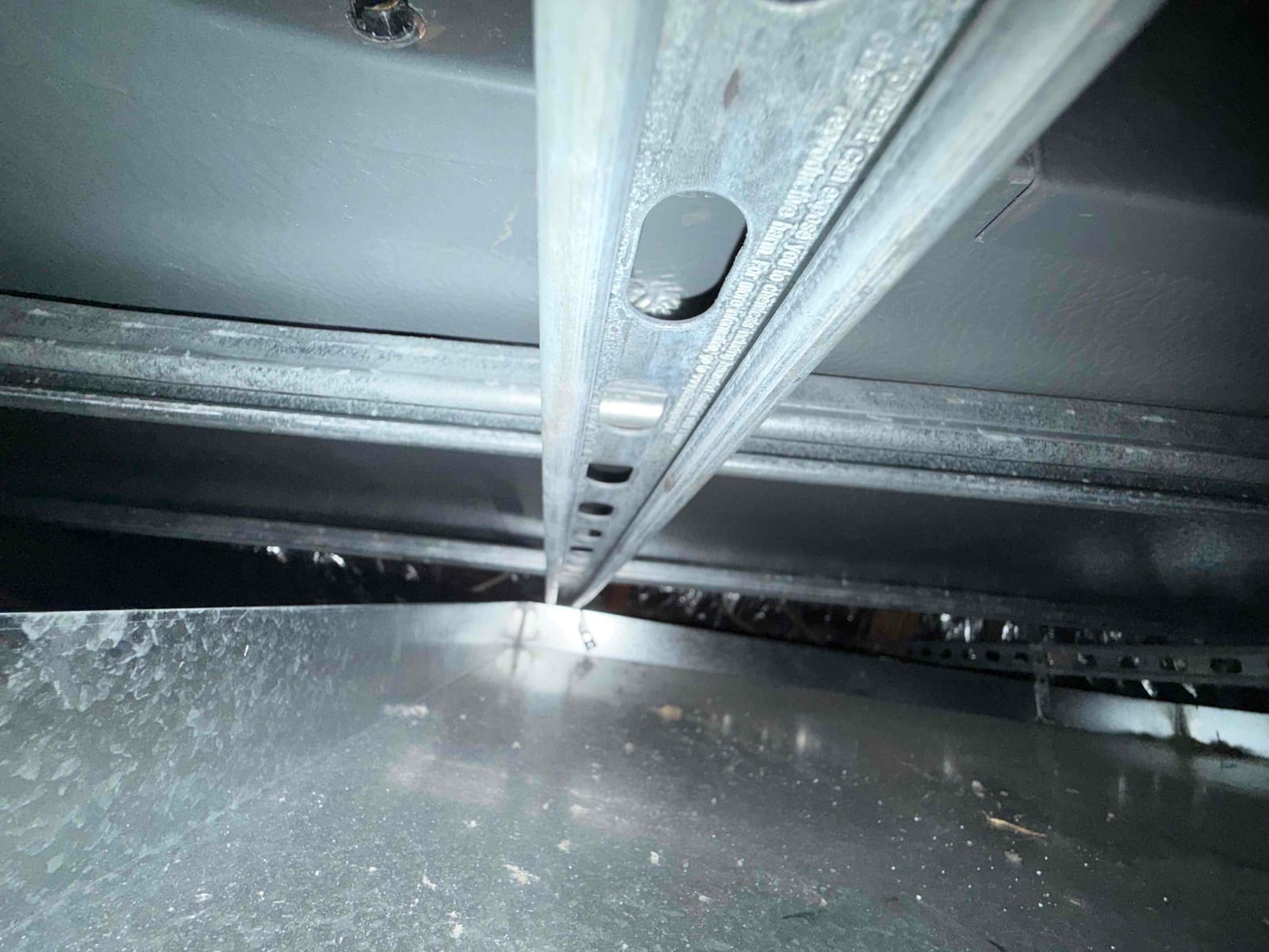 Galvanized sheet metal duct section with a slotted steel support channel spanning across the assembly.