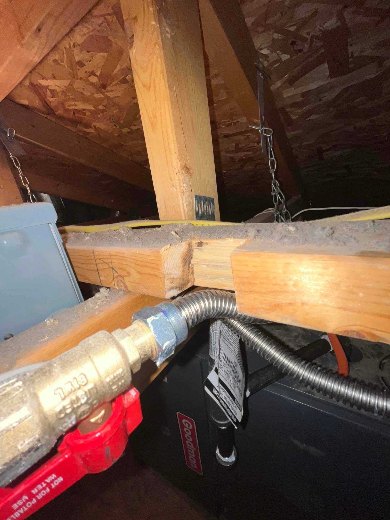 Gas shutoff valve with flexible connector and metal conduit entering a furnace cabinet within the attic framing.