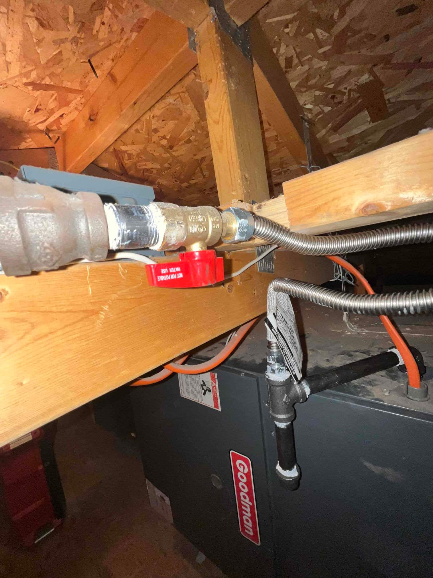 Gas shutoff valve with flexible connector and sediment trap installed above a furnace in the attic.