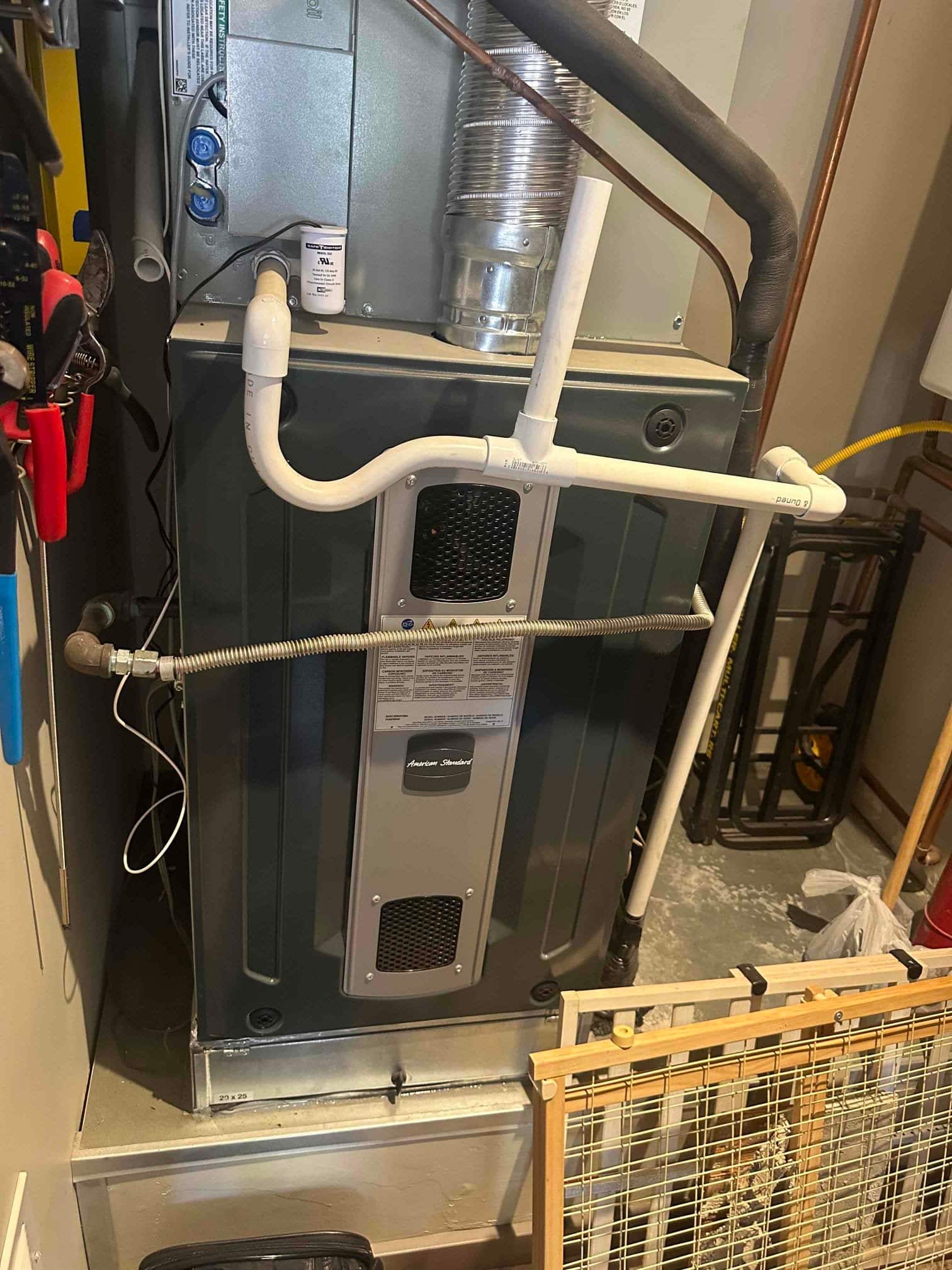Indoor gas furnace and evaporator section with condensate drain piping and float switch, insulated refrigerant line, flue vent, and flexible gas connector.