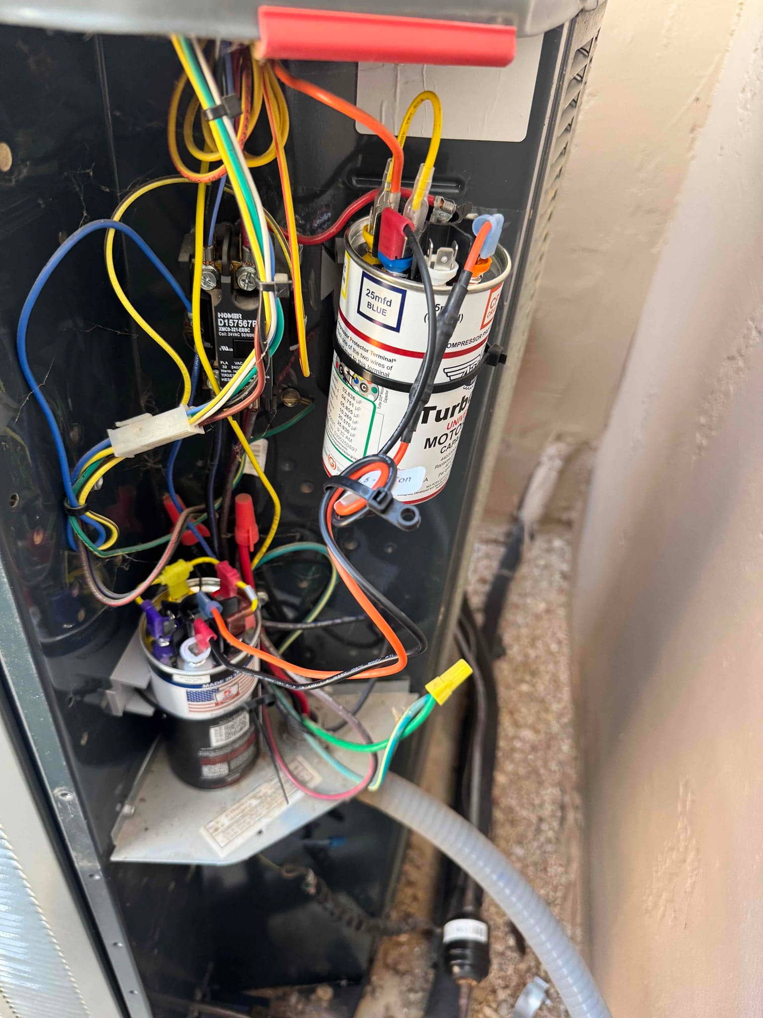 Open condenser control compartment shows multiple run capacitors and wiring, including a contactor. One capacitor labeled 25 mfd BLUE.